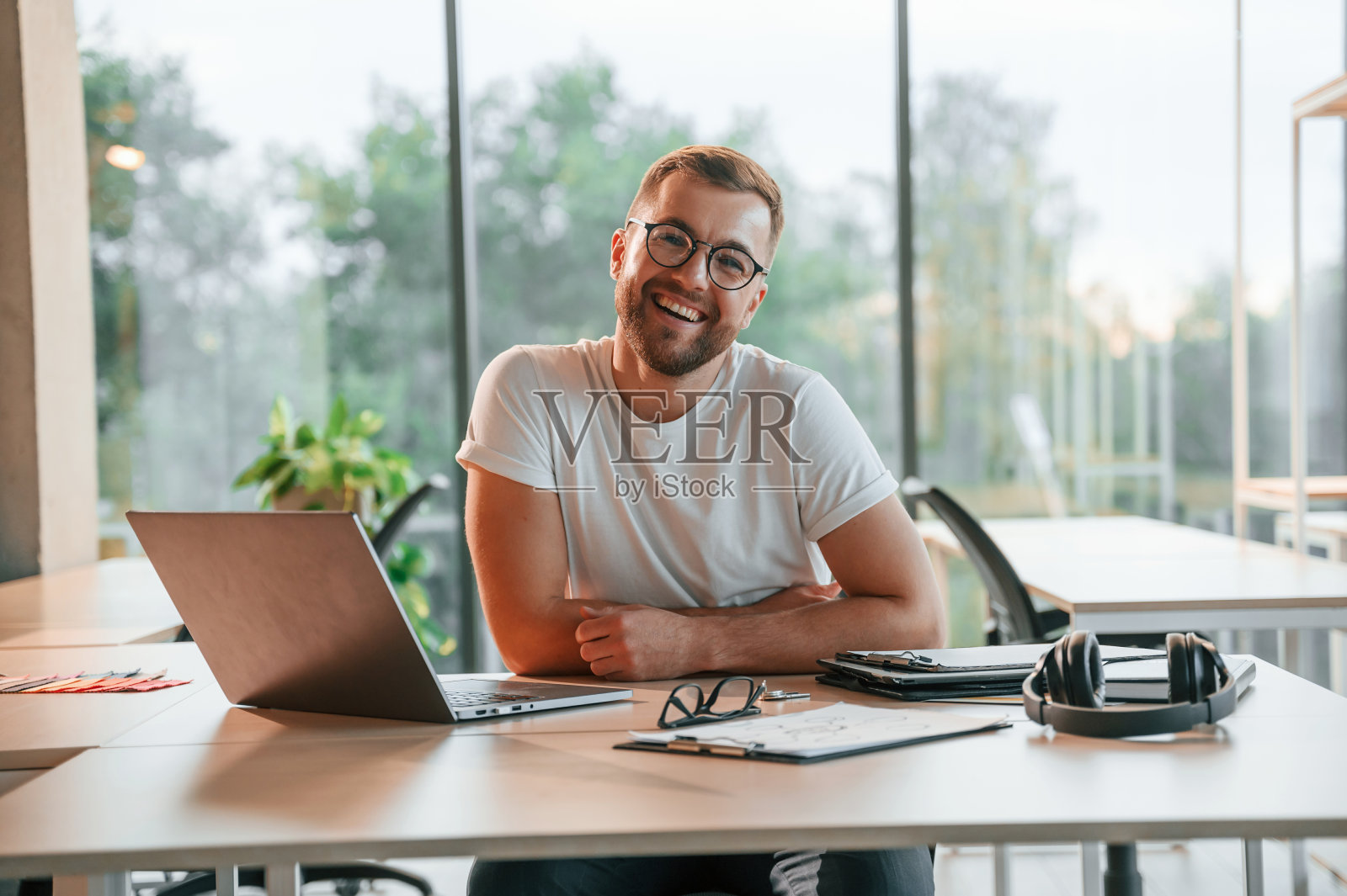 坐着微笑。穿着正装的积极男士在现代化的办公室里工作照片摄影图片