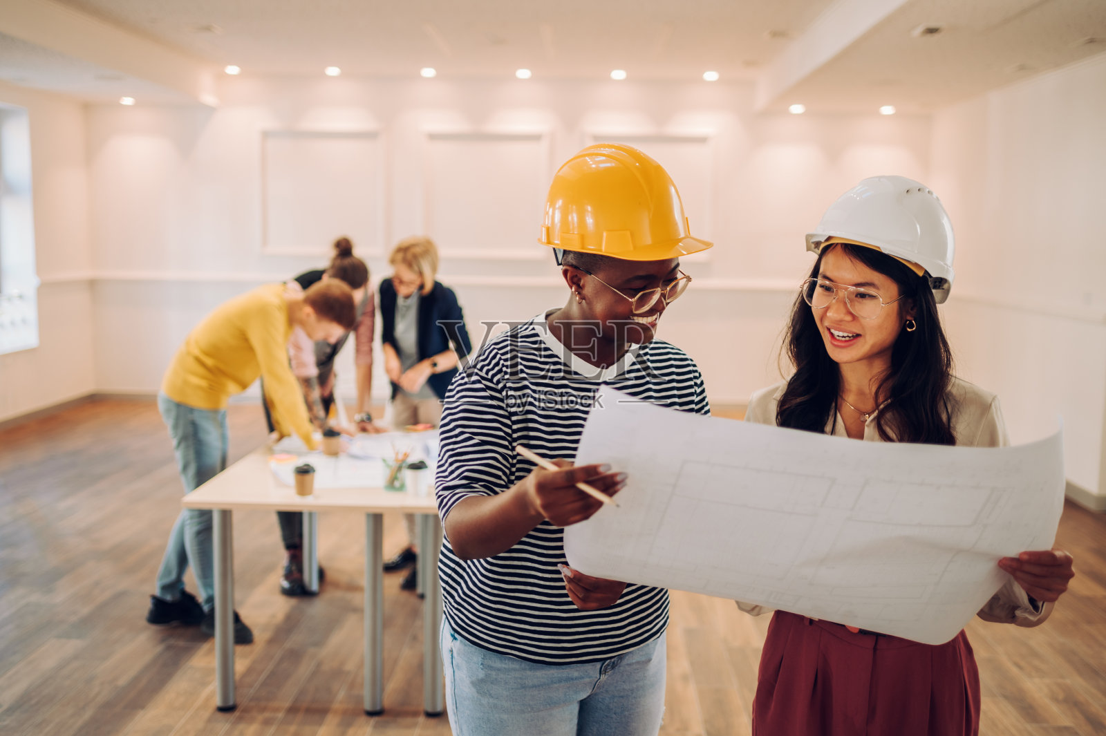 两位多种族建筑师在办公室里看蓝图的肖像照片摄影图片