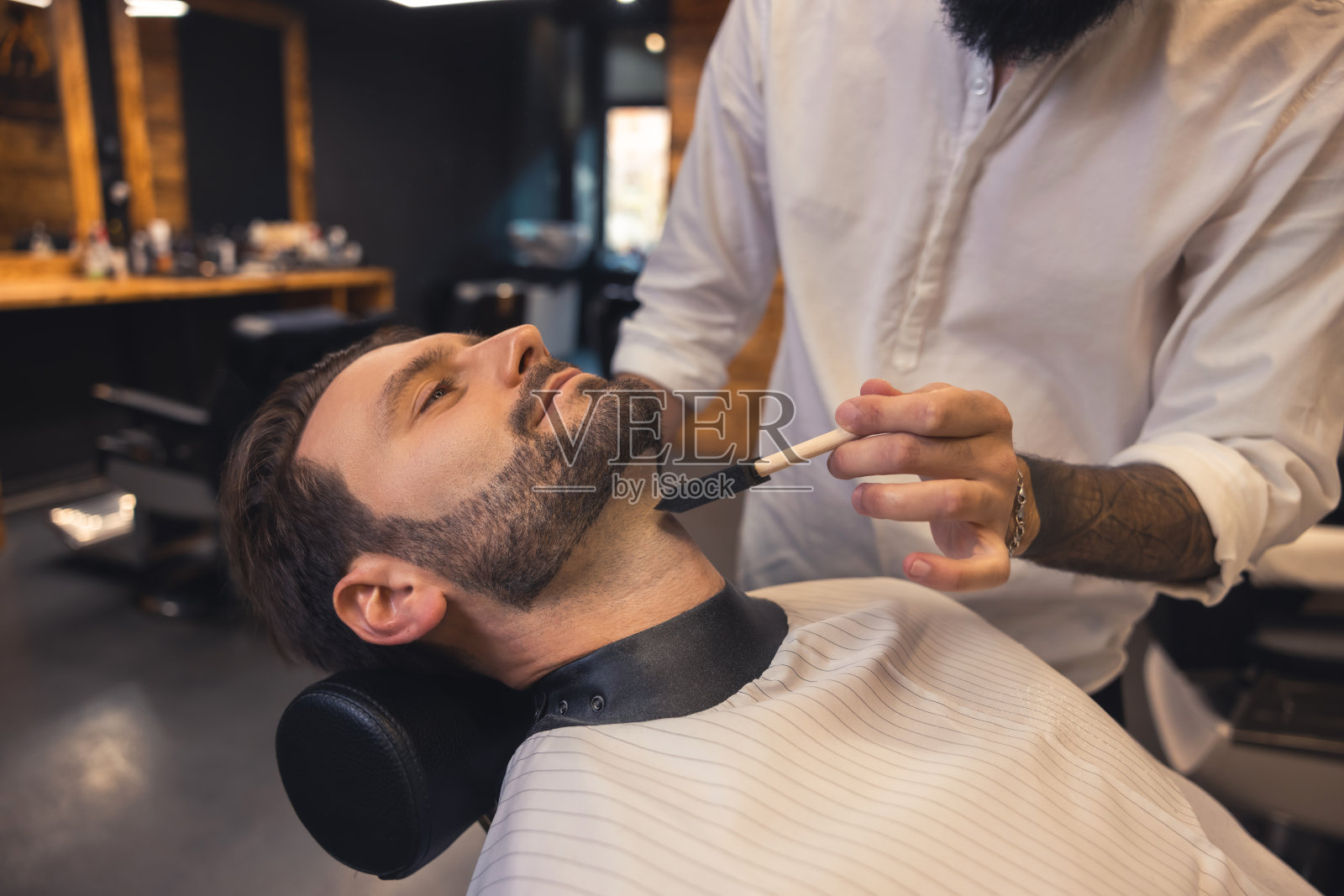 理发店里的理发师正在给顾客修胡子照片摄影图片