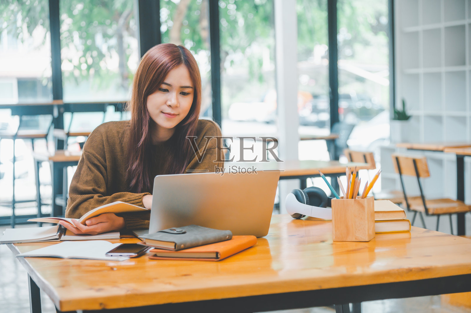 年轻的学生戴着耳机在线学习，远程学习，并随时了解全球冠状病毒大流行的最新情况。照片摄影图片