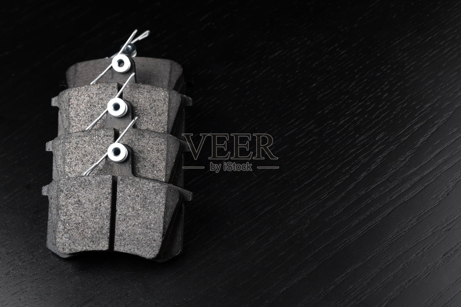 一套新的汽车零部件。新的刹车片在黑色木制背景上，复制空间。一组制动部件汽车商店或汽车服务的概念。照片摄影图片