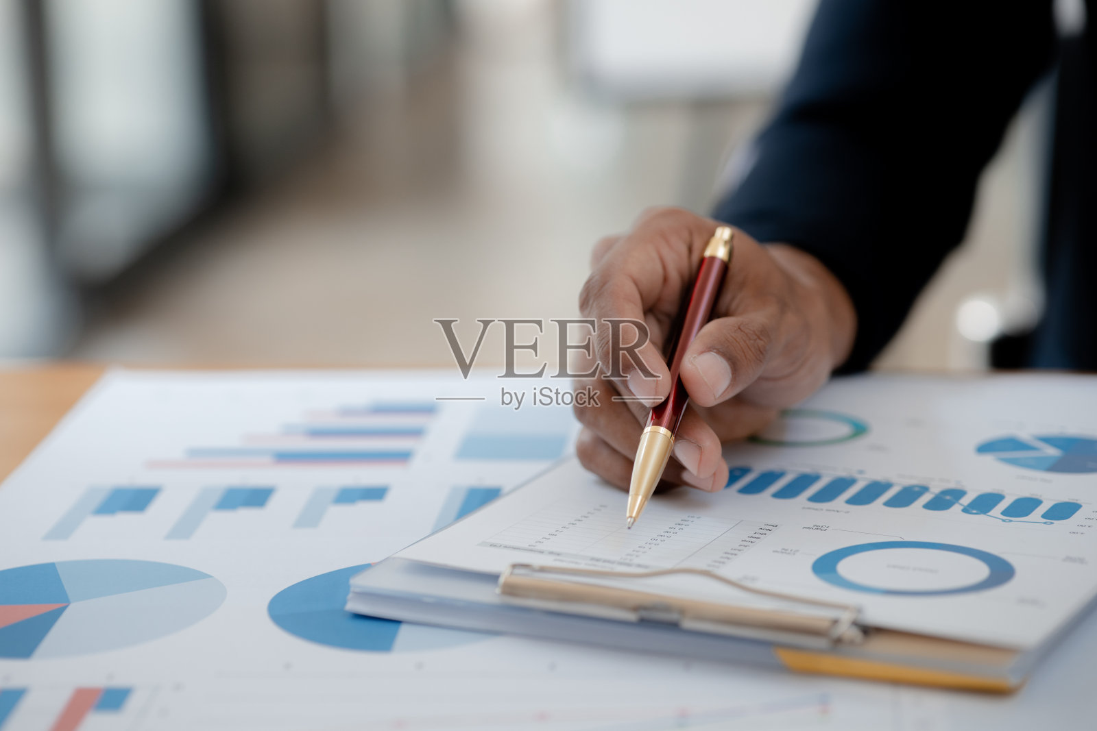 一名商人坐在她的私人办公室里，指着一份显示公司财务信息的饼状图。这是一份以图表形式显示公司财务信息的文件。金融的概念照片摄影图片