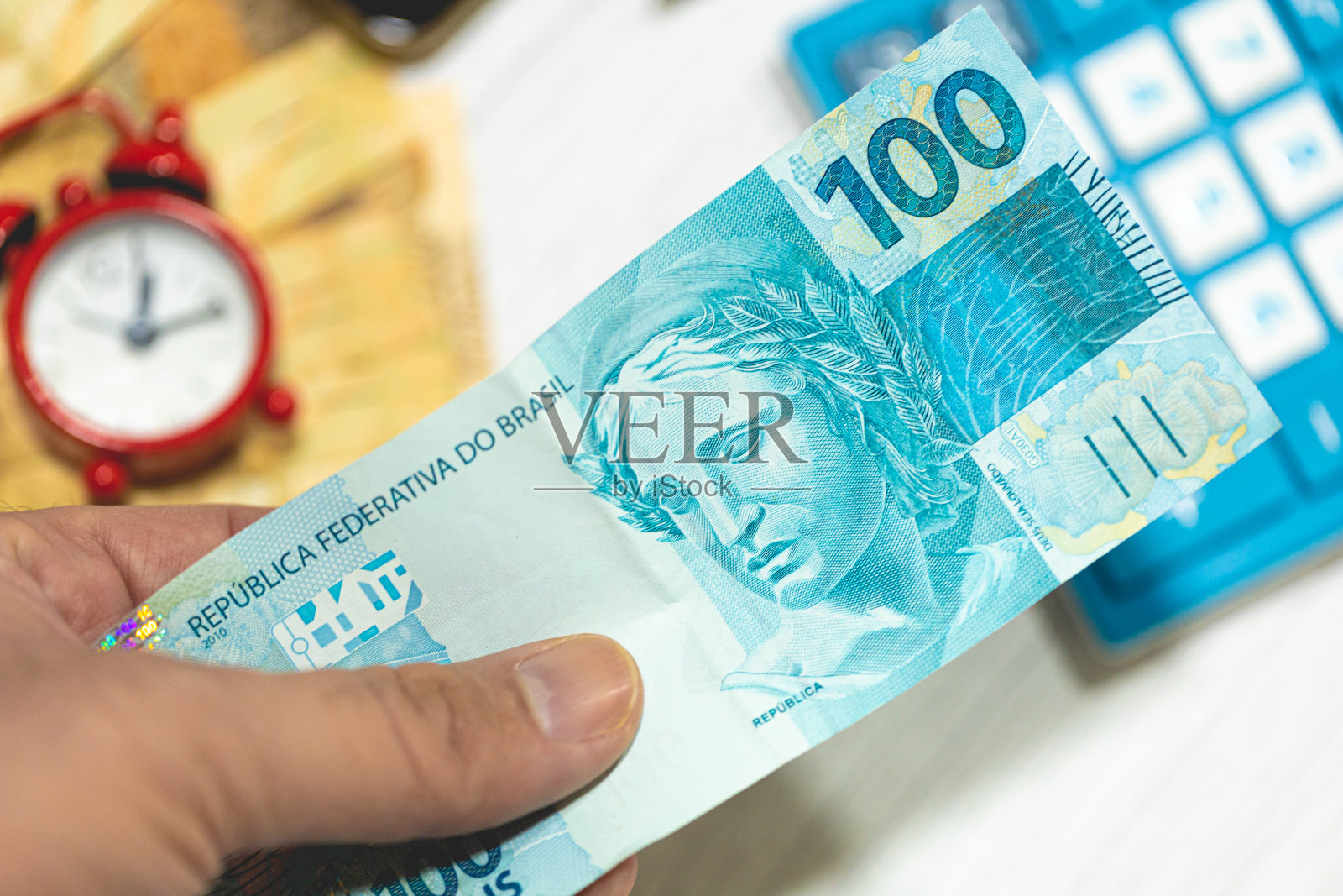 一名男子手里拿着价值100雷亚尔的巴西雷亚尔钞票。巴西经济和金融。照片摄影图片