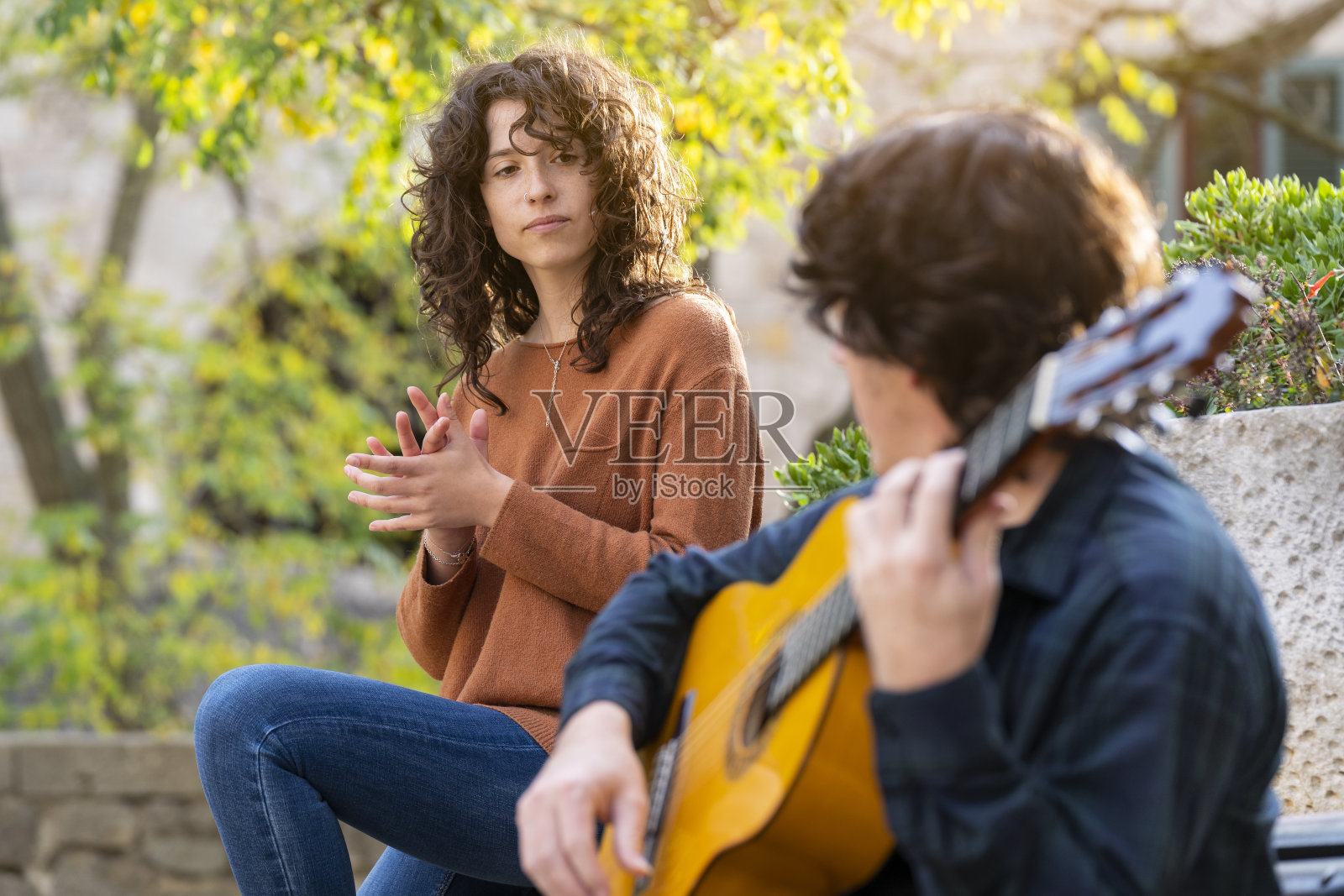 年轻的卷发女人在街上和吉他手唱歌照片摄影图片