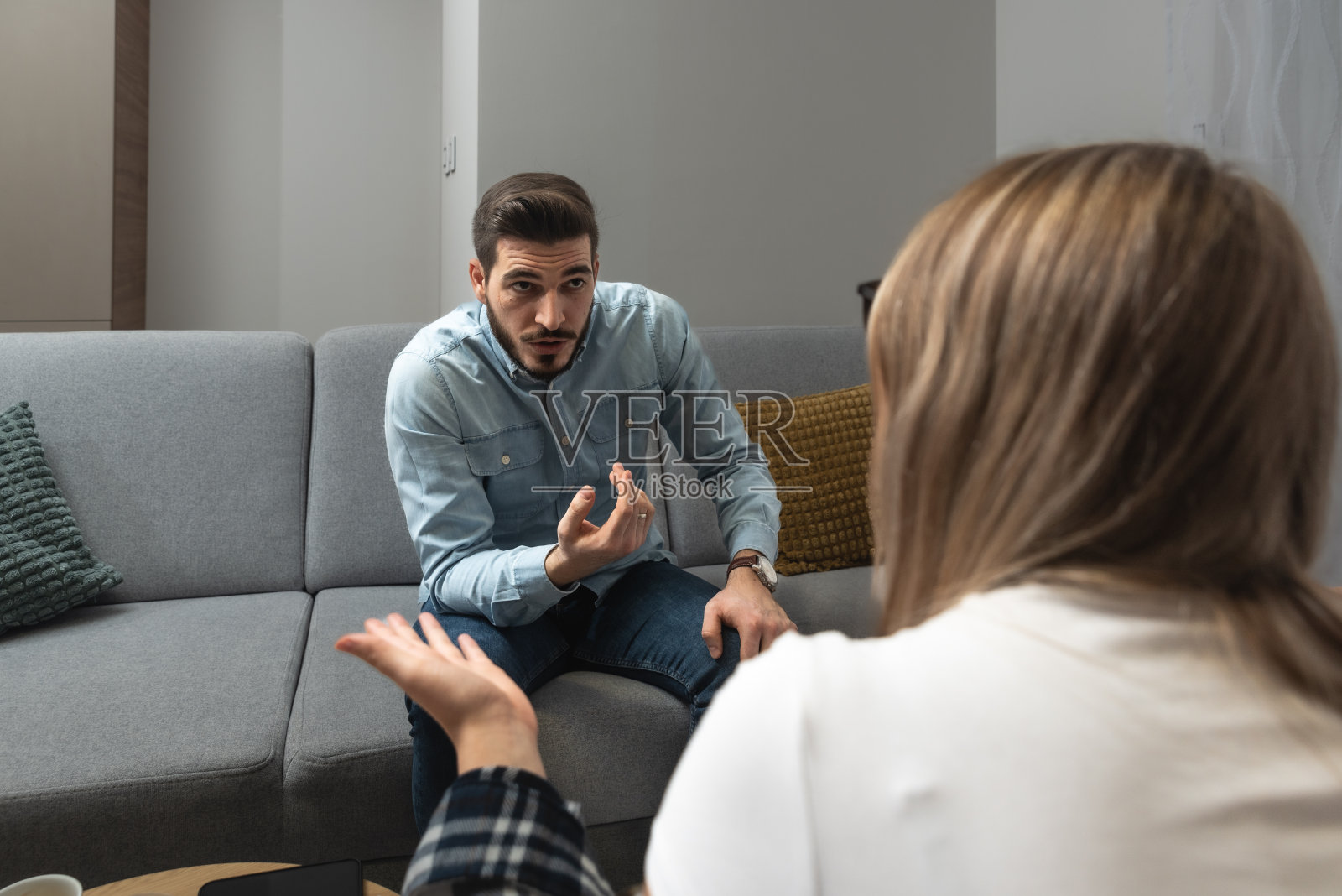 年轻的夫妻夫妻坐在家里，他们的婚姻出现了问题，关系冷淡。一个男朋友和一个女朋友因为花钱太多而争吵。照片摄影图片