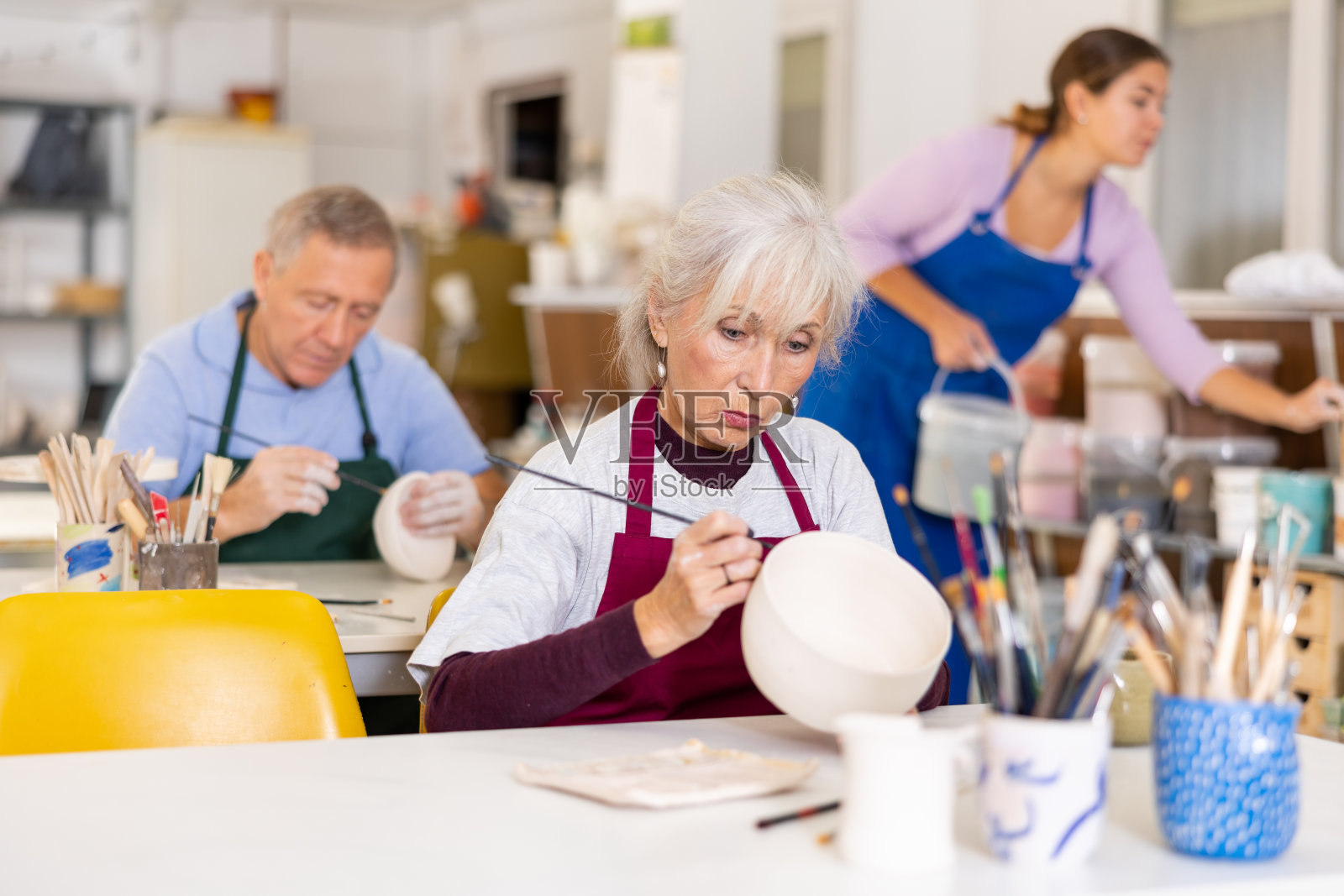 女陶工拿着画笔，在车间的板上作画，在工作室工作照片摄影图片