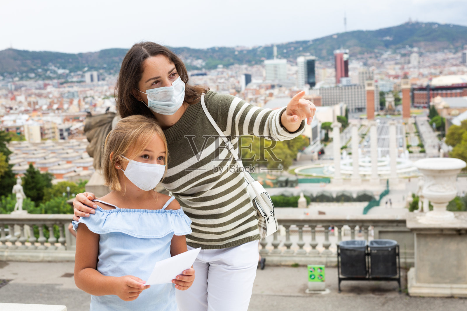 母亲和女儿戴着防护口罩走在欧洲夏城的街道上照片摄影图片