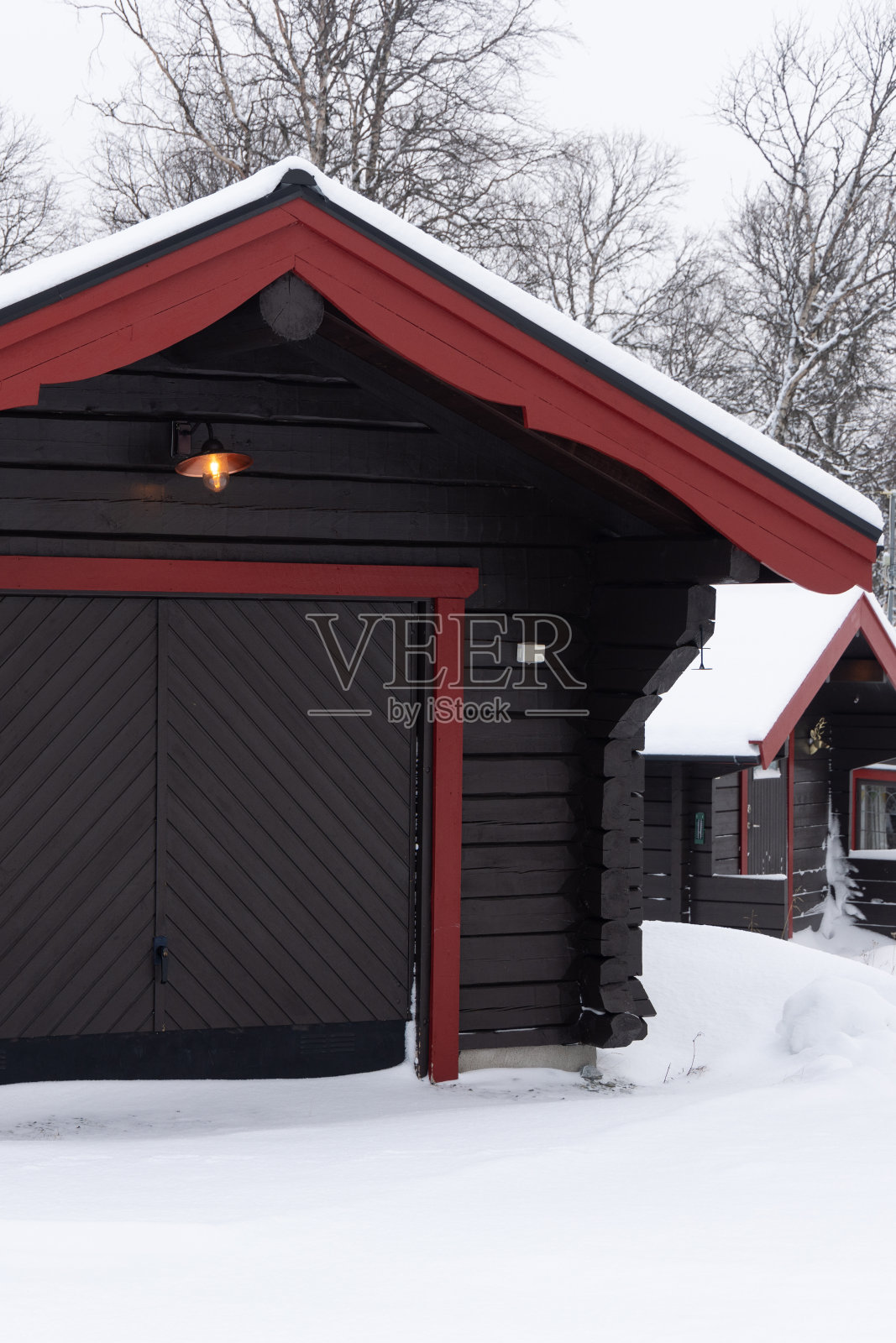 美丽的小木屋，在阳光明媚的冬日被森林环绕的小屋。瑞典的滑雪胜地，Funasdalen被白雪覆盖照片摄影图片