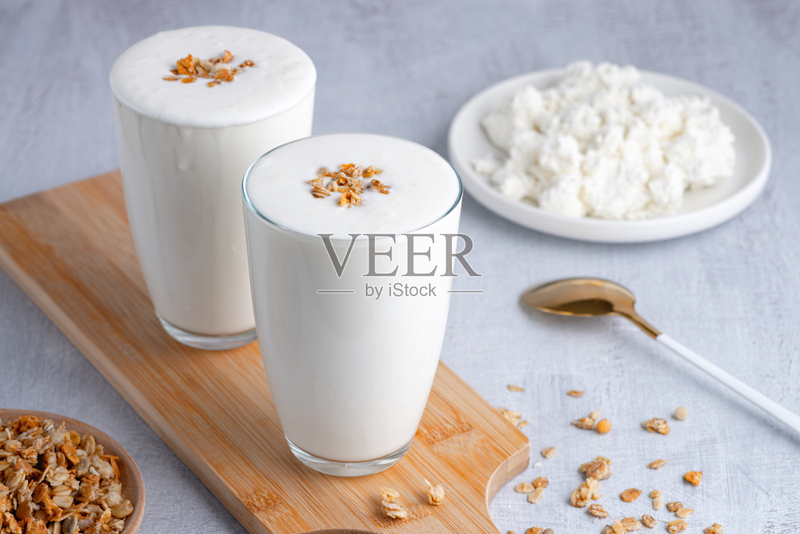 开菲尔，酪乳或酸奶，白软干酪配格兰诺拉麦片。酸奶装在玻璃杯里，白色木制背景。益生菌冷发酵乳饮料。肠道健康，发酵产品，健康肠道菌群概念。本空间照片摄影图片