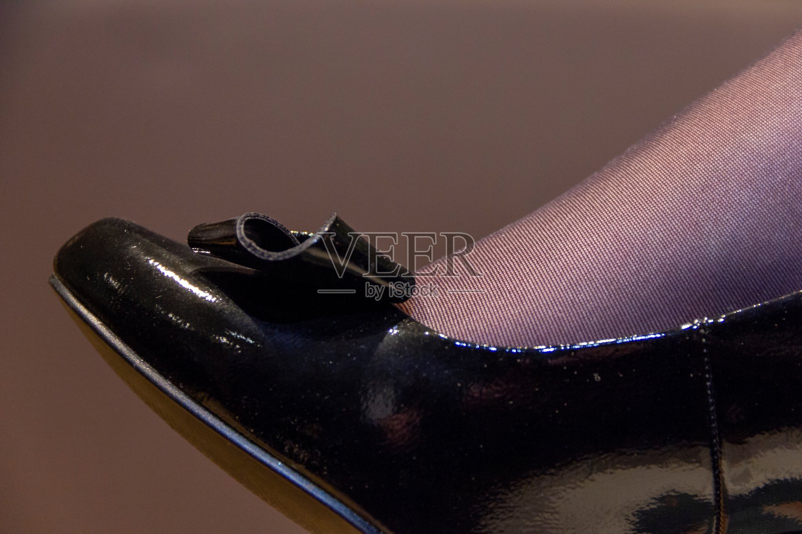 一个近距离肖像的脚尖穿着一双黑色尼龙丝袜和黑色闪亮的高跟鞋与领结的尖端。照片摄影图片