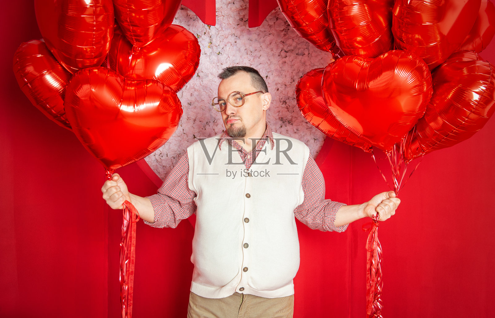 滑稽悲伤的胡子复古风格男子在白色背心拿着红色心形气球照片摄影图片