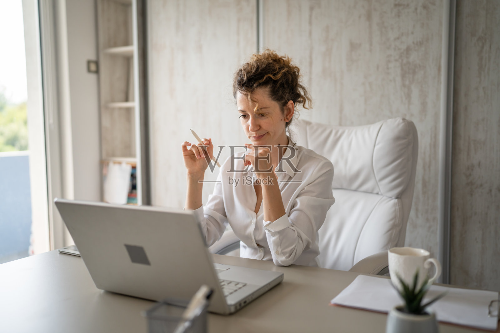 一个年轻的女商人回到办公室用笔记本电脑工作照片摄影图片