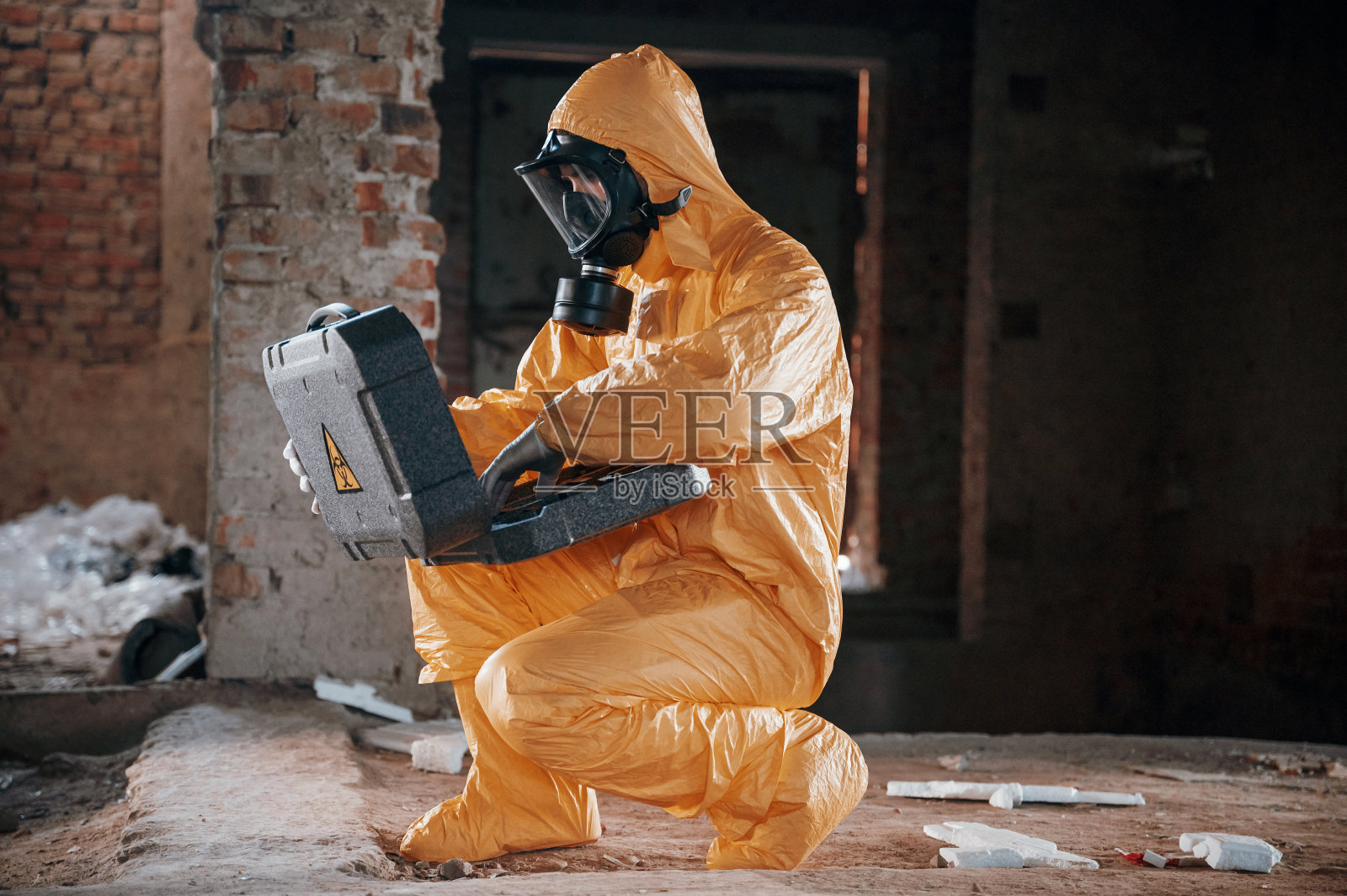 和放射性病例坐在一起。一名穿着化学防护服的男子站在后启示性建筑的废墟中照片摄影图片