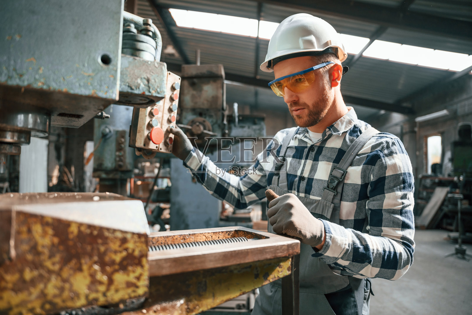 专注于工厂机器的工作。穿制服的工人在室内照片摄影图片