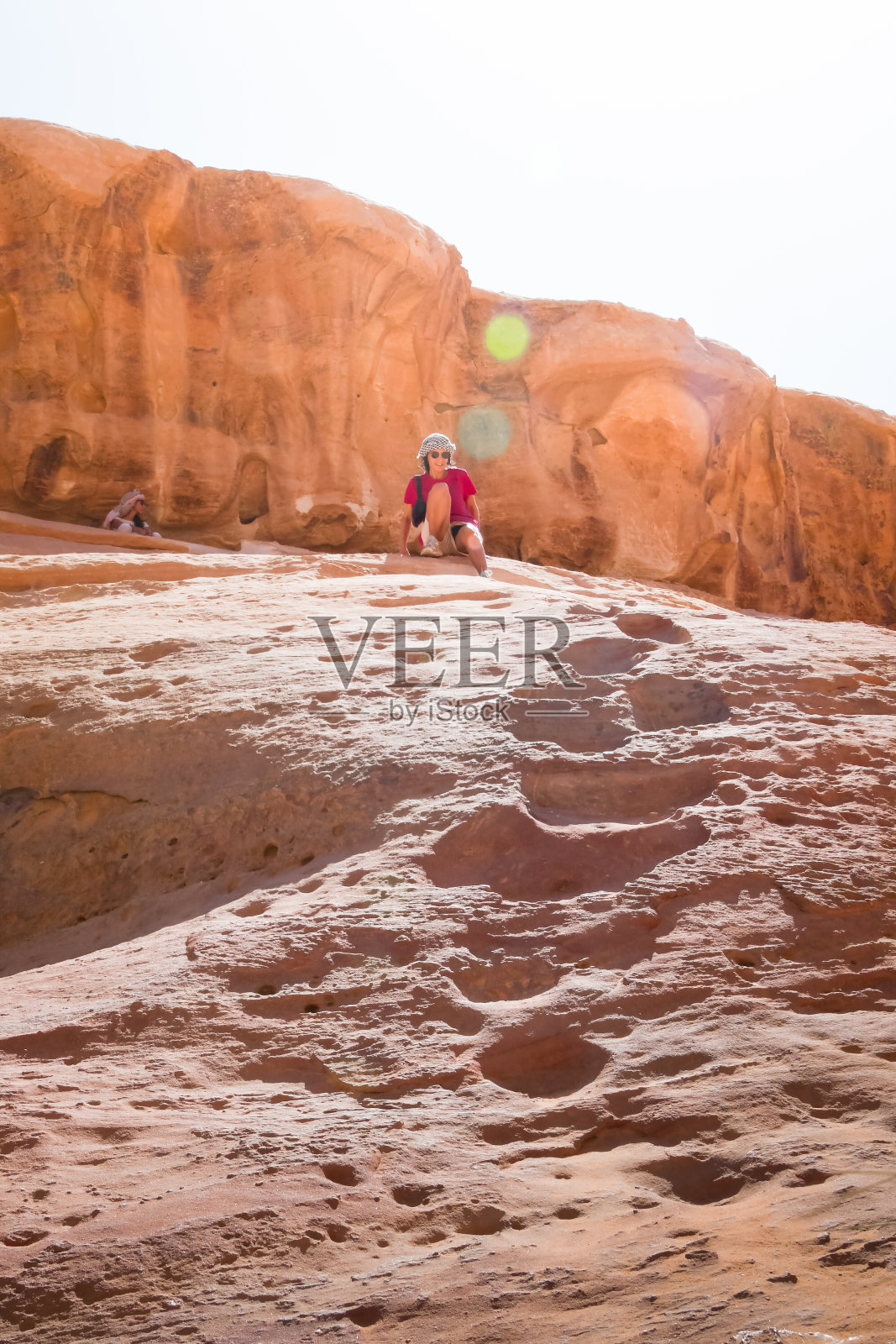 年轻的白人女孩在瓦迪拉姆沙漠度假时从岩层上爬下来，勇敢面对自然照片摄影图片
