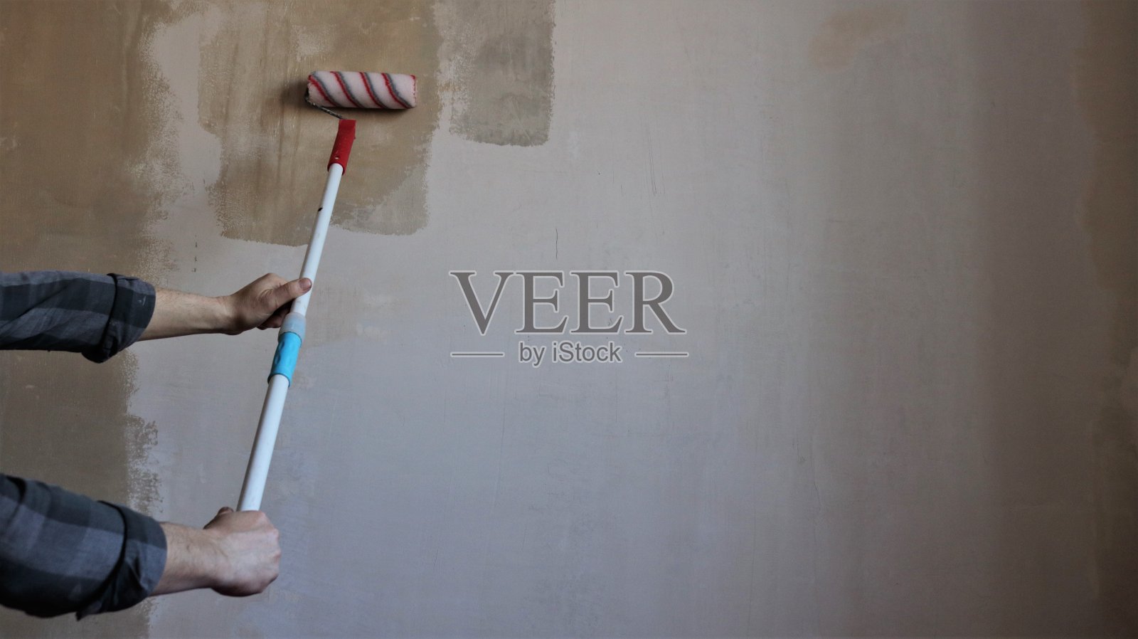 用长柄滚轮在房间墙壁上打底照片摄影图片