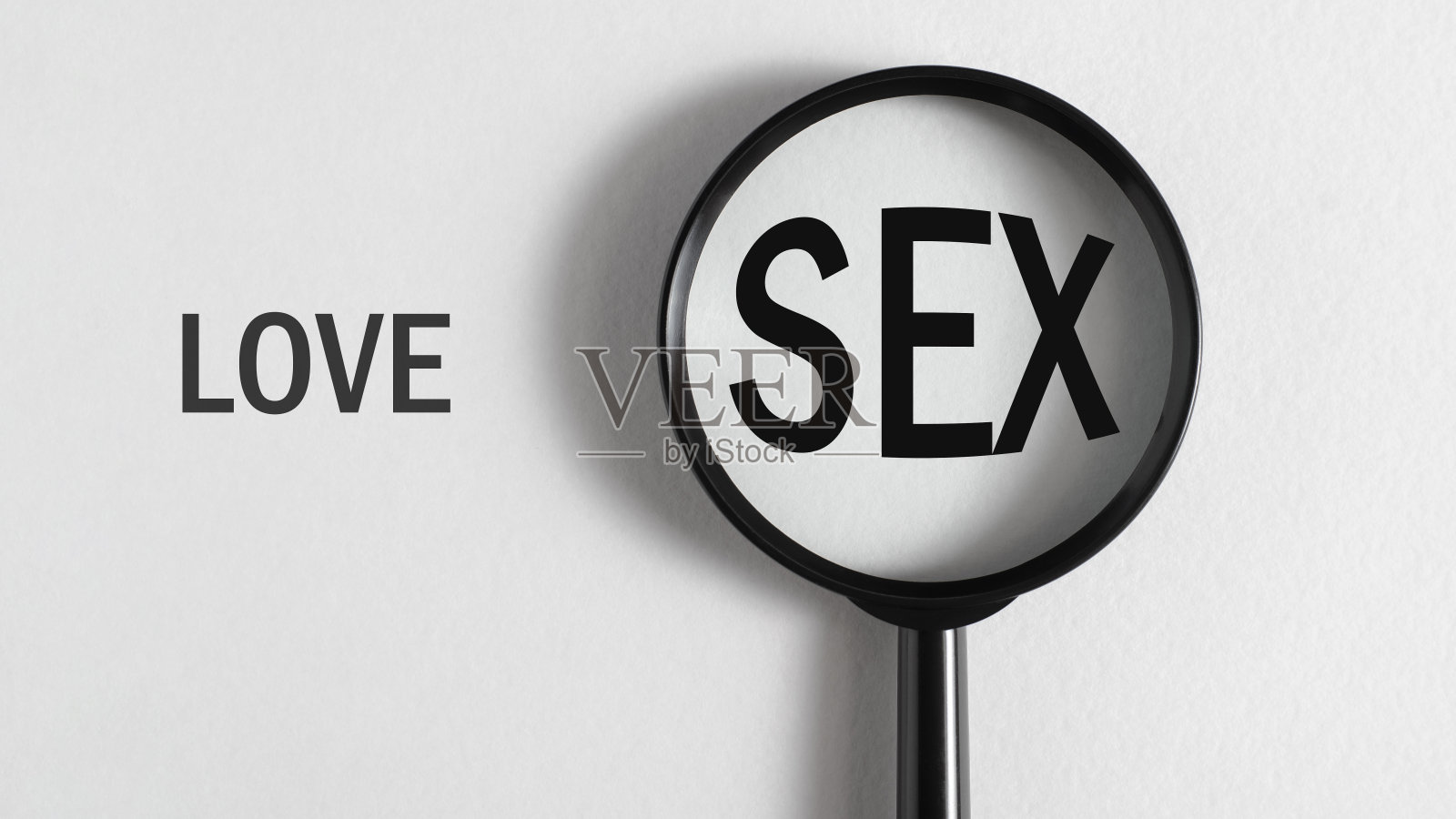 选择的概念，关系问题。近距离放大镜聚焦在白色背景上的“性”和“爱”两个字上照片摄影图片