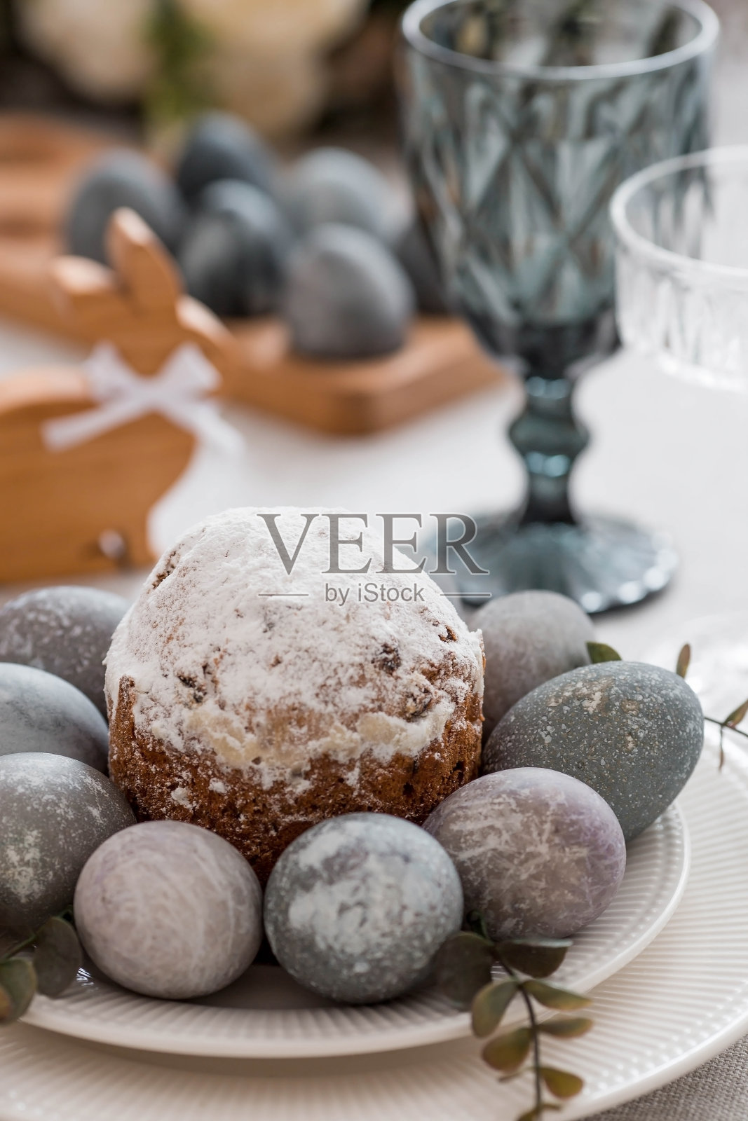 弹簧桌设置。一个盘子，一个有兔子的棉餐巾，一个蛋糕和复活节彩蛋。银器，复活节兔子，亚麻桌布上的花瓶。一个明亮的复活节假期的概念。照片摄影图片