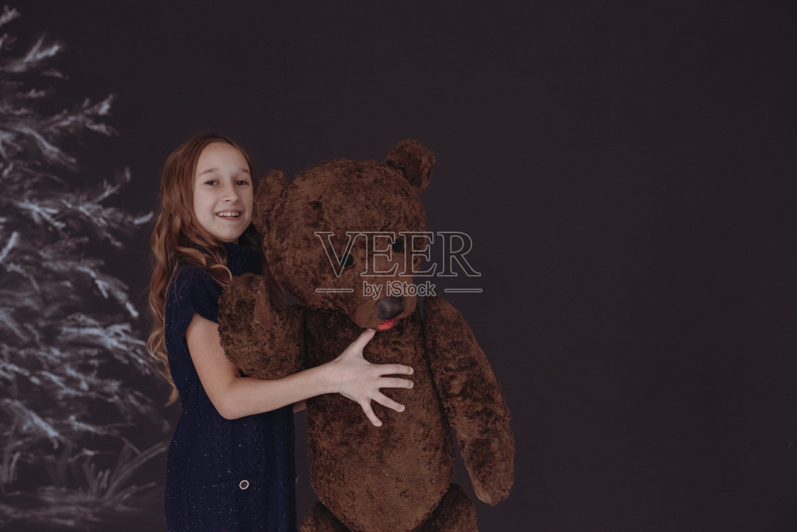 这个女孩手里拿着一只大的交易熊。照片摄影图片