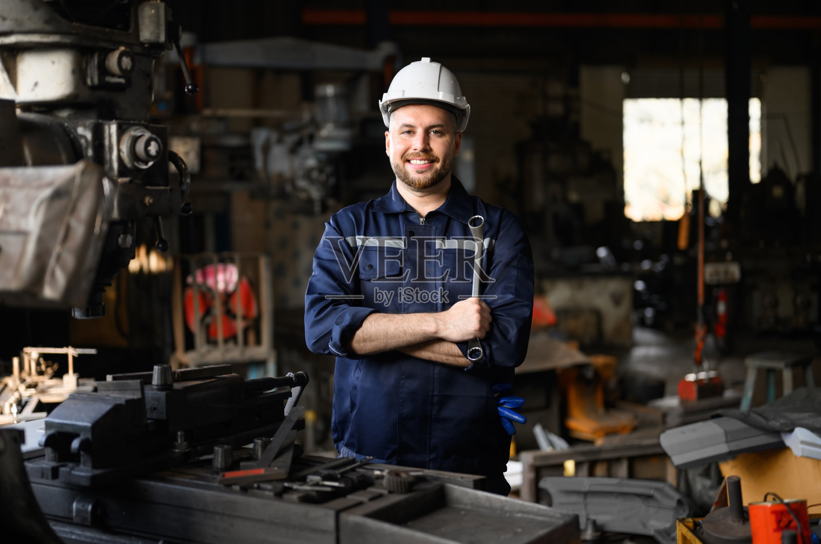 快乐的机械工程师的肖像，微笑着手臂交叉在工厂修理机器照片摄影图片