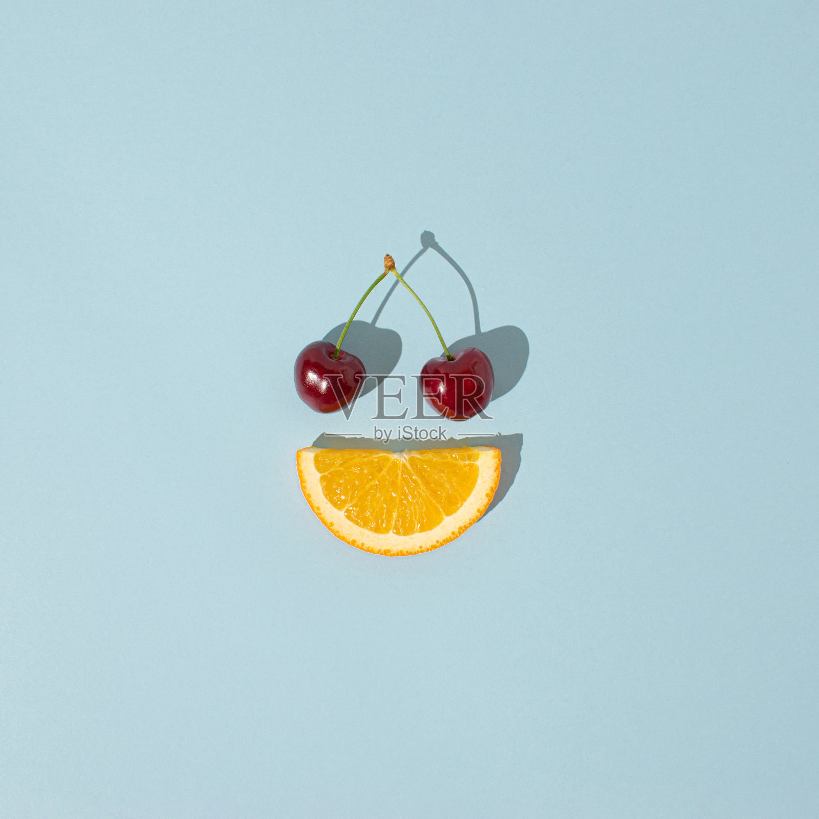 樱桃和橙片在明亮的蓝色背景。夏日水果创意概念。照片摄影图片
