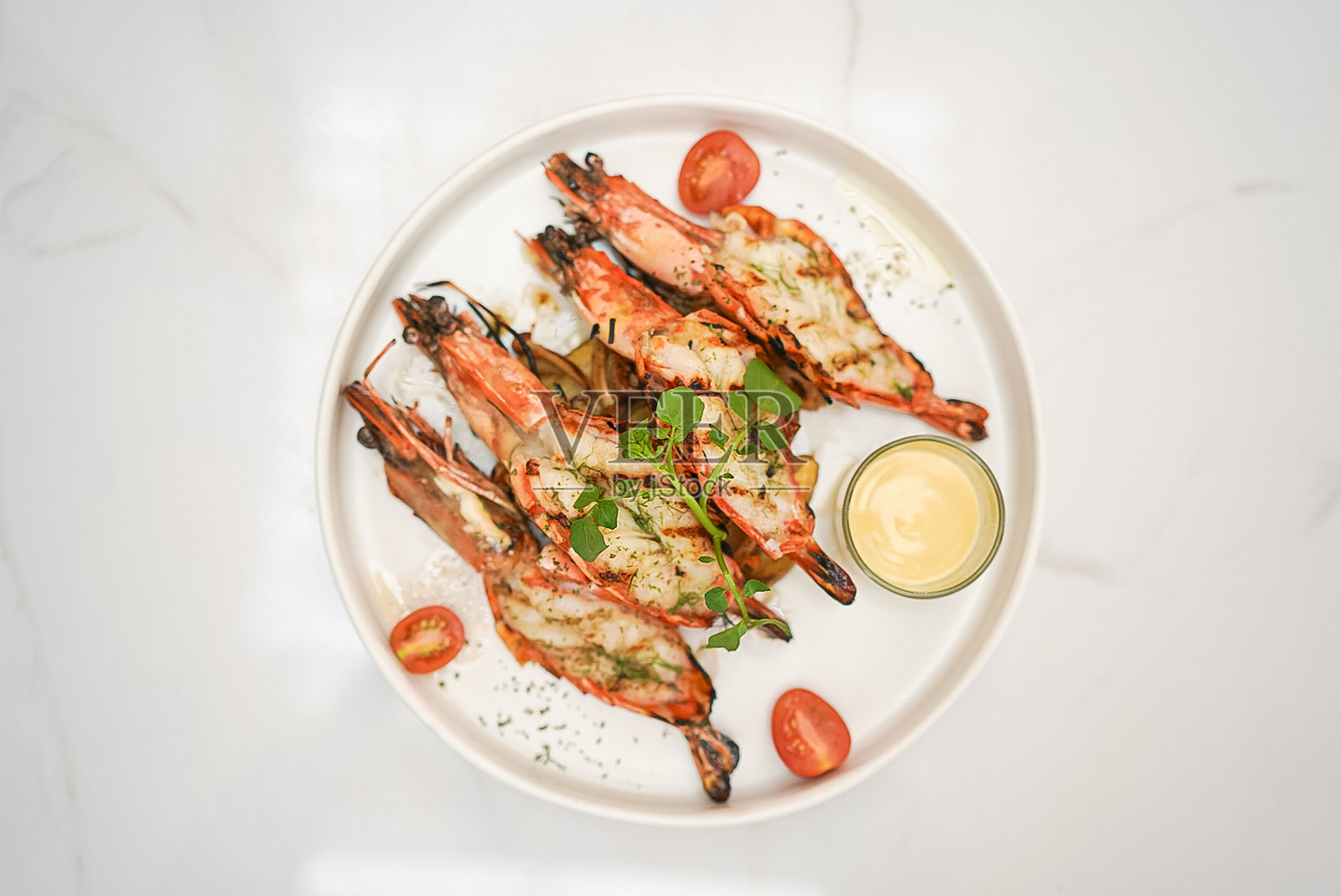 白盘子里的烤虾和酱汁照片摄影图片