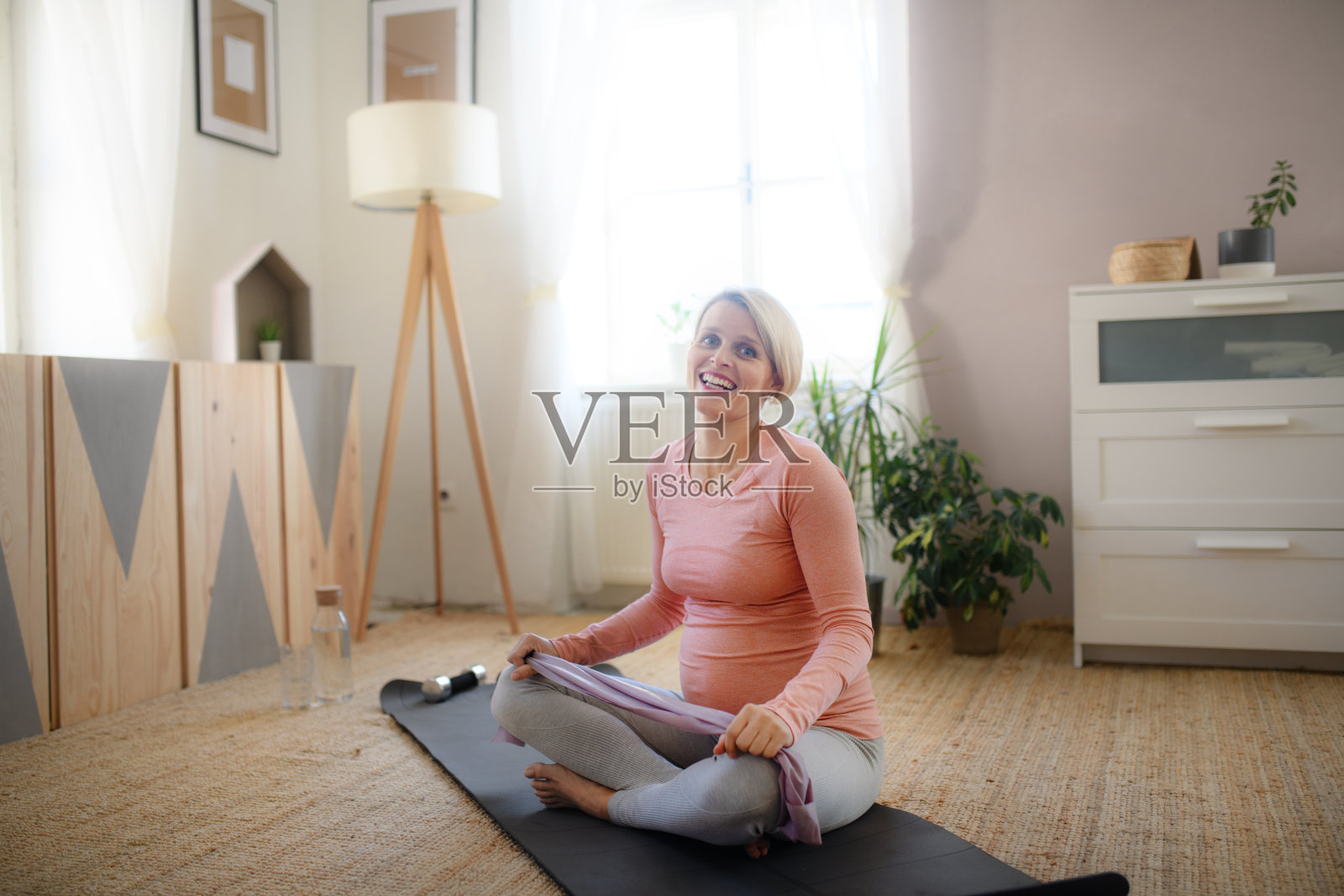 一个孕妇在她的公寓里做运动。照片摄影图片