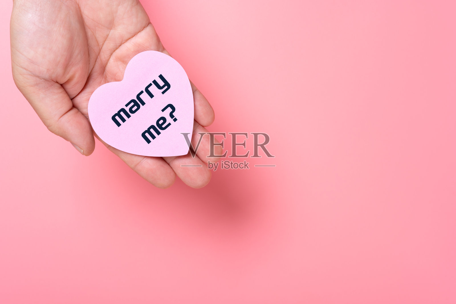 男人拿着一张写着“嫁给我”的心形纸照片摄影图片