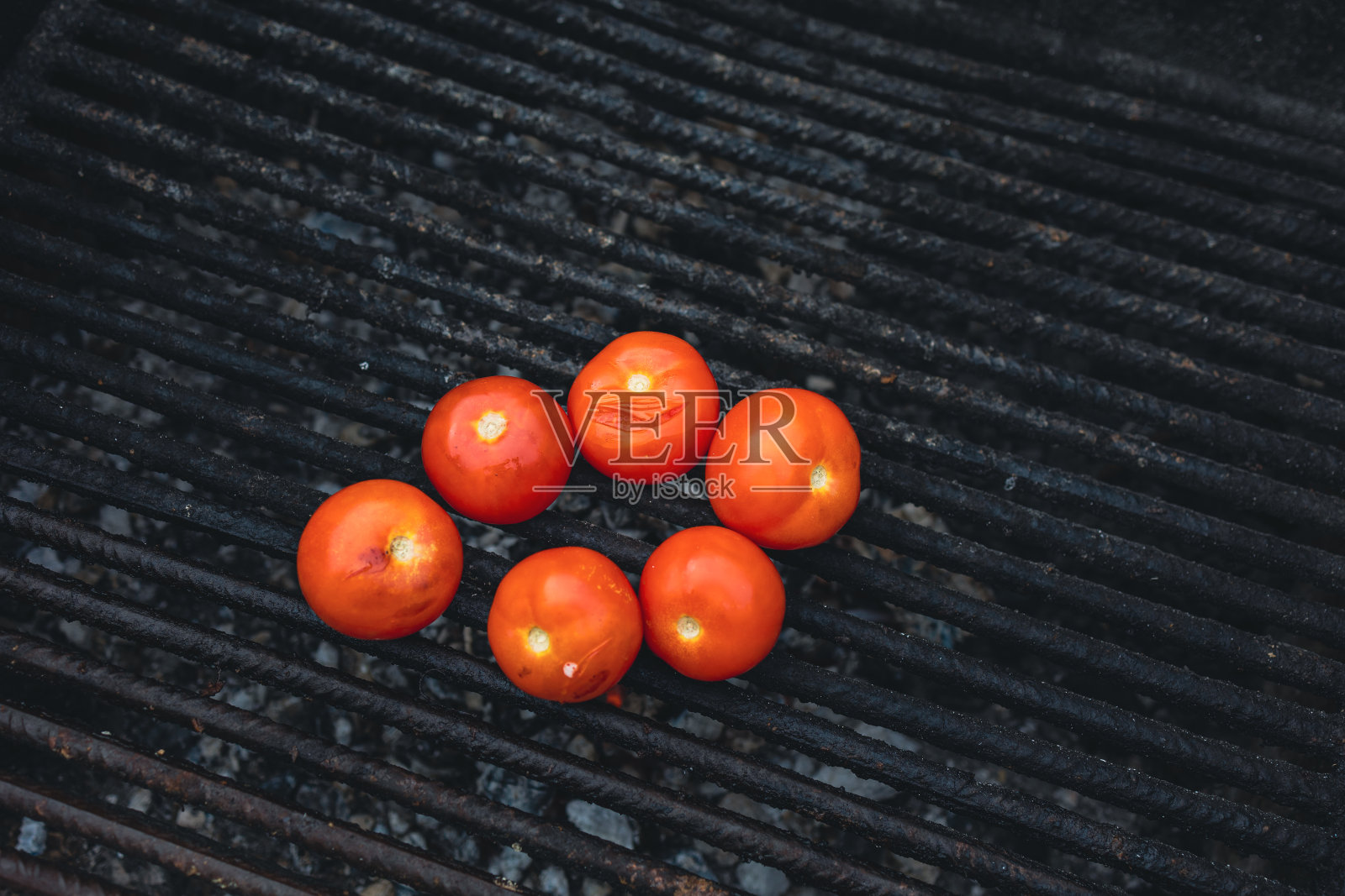 烧烤架上的几个西红柿，是野餐时烤的。照片摄影图片