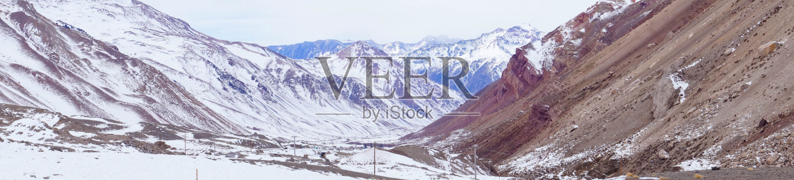 乌云密布的蓝天下，雪山的全景。照片摄影图片