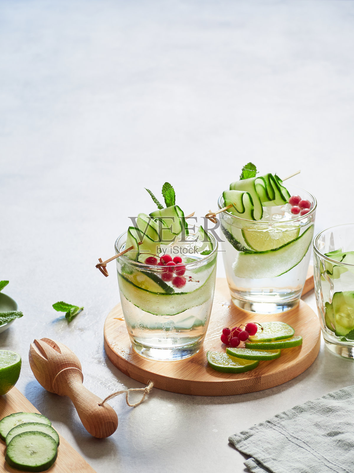 新鲜黄瓜水与青柠，薄荷和红醋栗。用细黄瓜条串在烤串上装饰。照片摄影图片