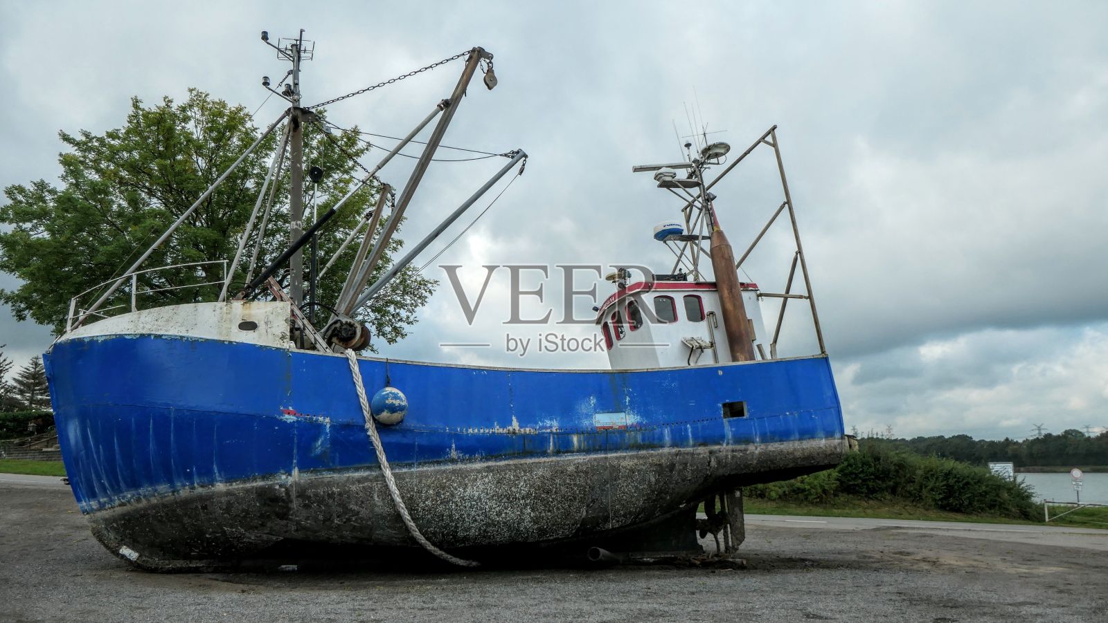 废弃的蓝色渔船在德国北Ostsee Kanal，背景是树木照片摄影图片