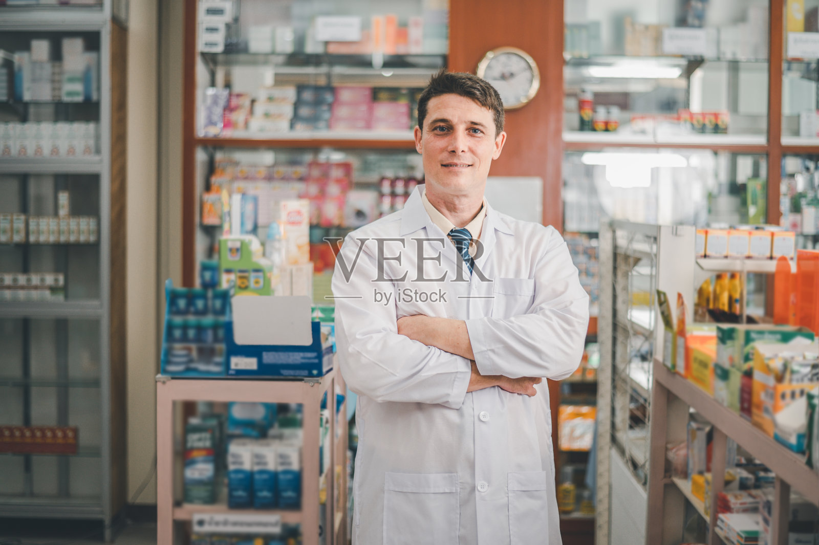 男性药剂师摆出自信的姿势欢迎，建议病人和处方病人在现代药房。照片摄影图片