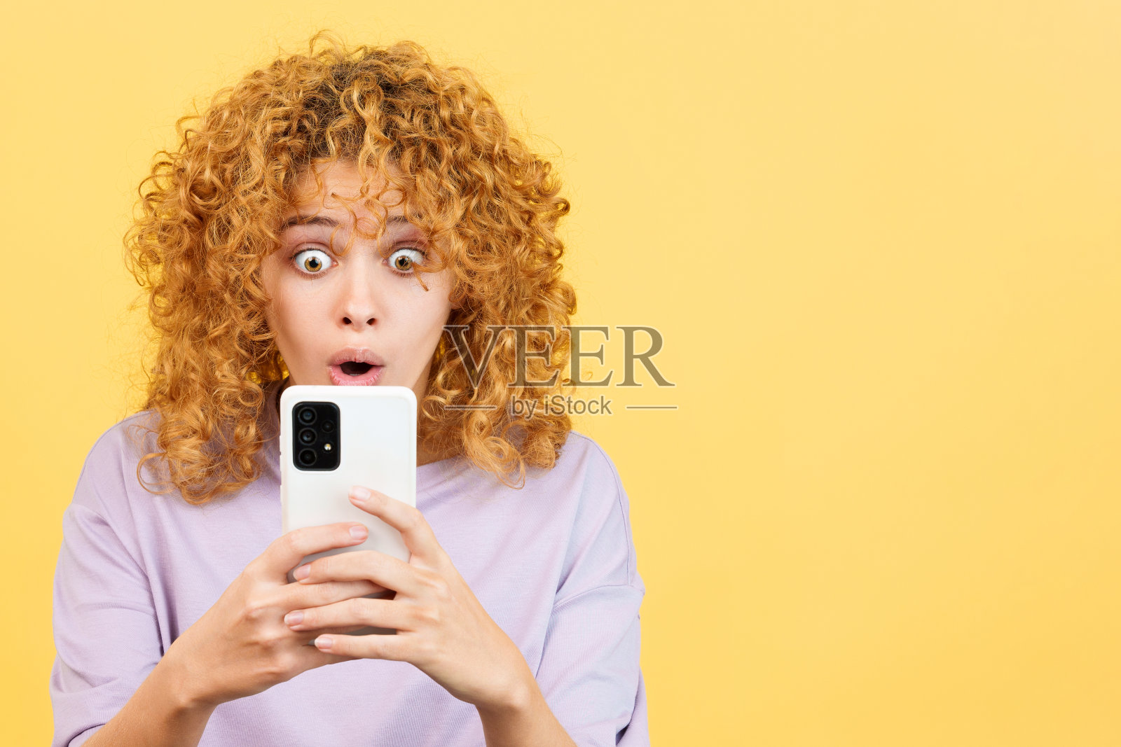 惊讶的卷发女人用手机照片摄影图片