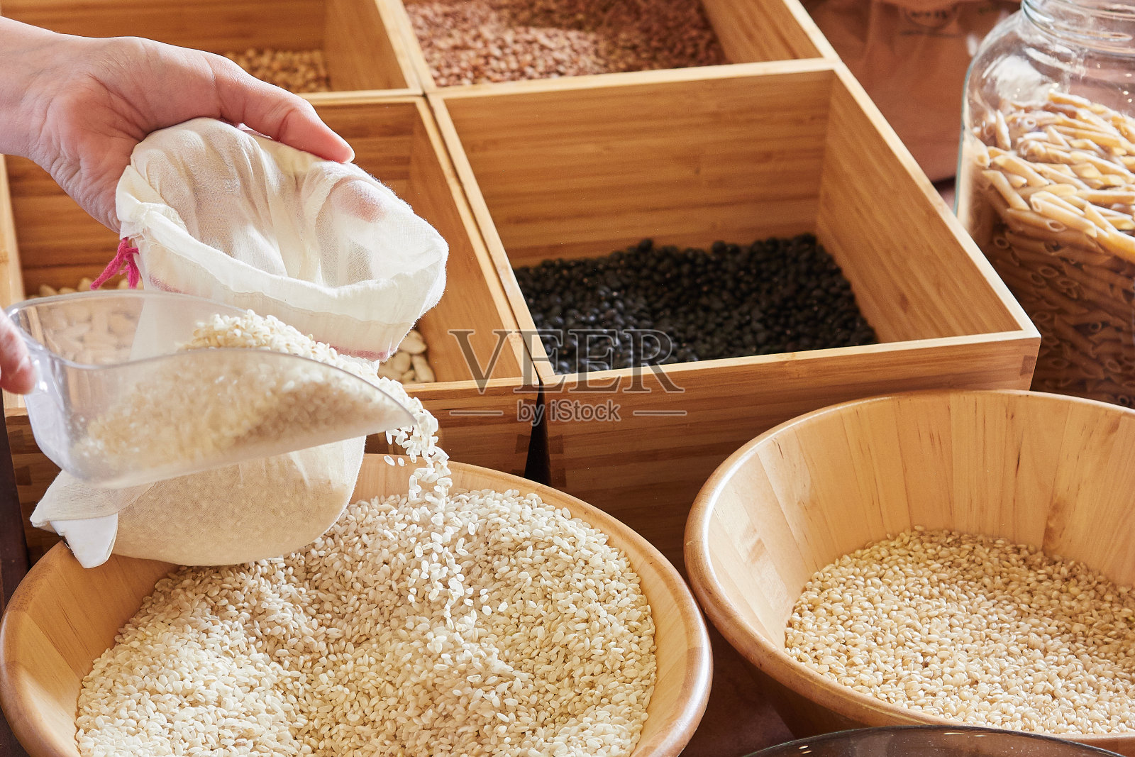 在当地的小杂货店里，手将可重复使用的布袋装满大米，用可持续包装批量购买概念照片摄影图片