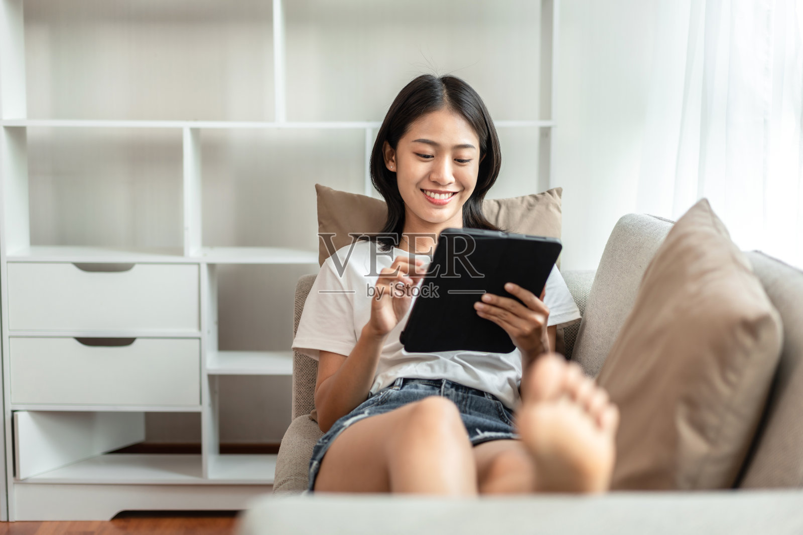 一半日本女人坐在沙发上使用平板电脑度假，在家休息，客厅，放松时间，触摸屏平板电脑，上网，最喜欢的角落，个人空间照片摄影图片