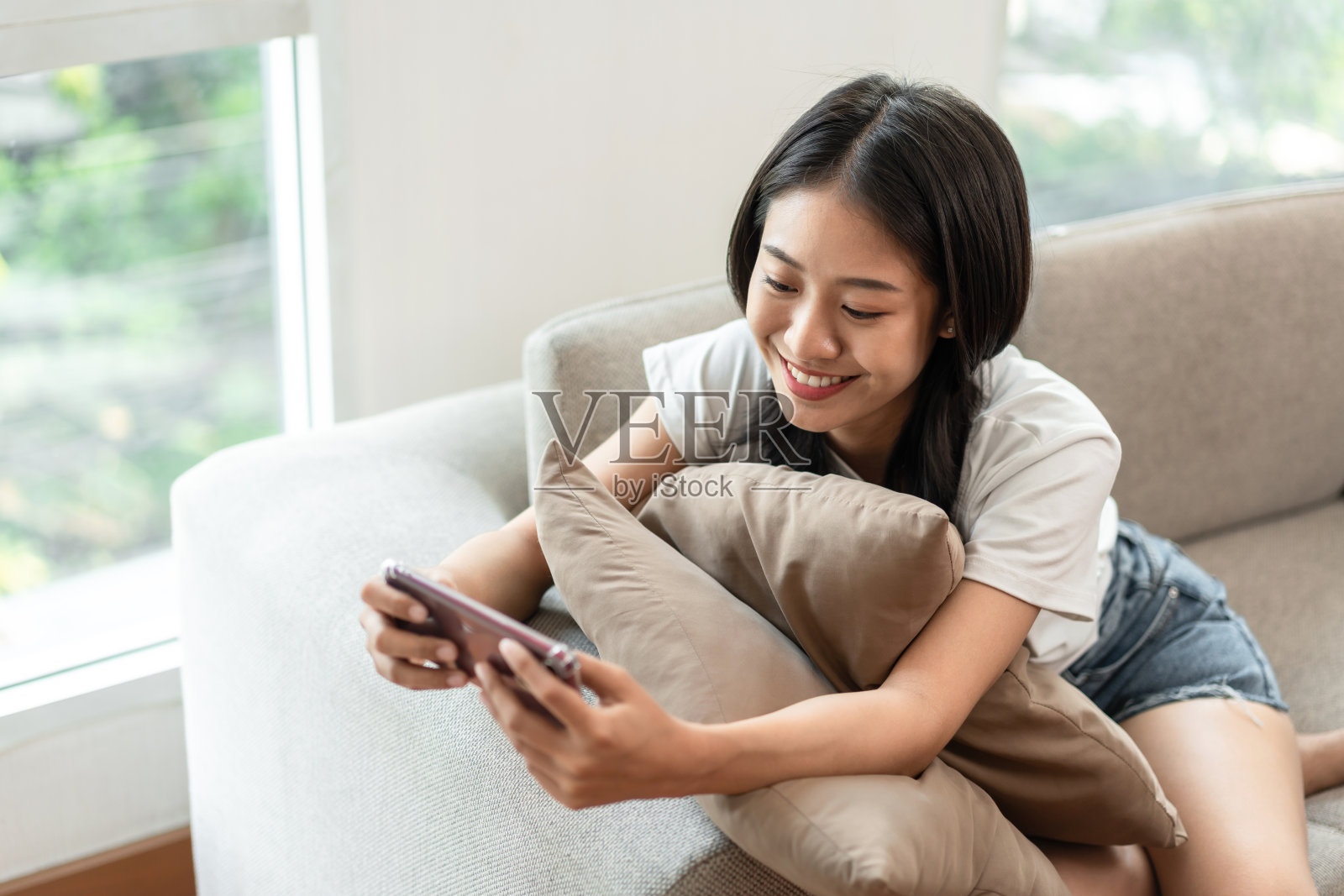 一半日本女人坐在沙发上使用手机度假，在家休息，客厅，放松时间，触摸屏平板电脑，上网，最喜欢的角落，个人空间照片摄影图片