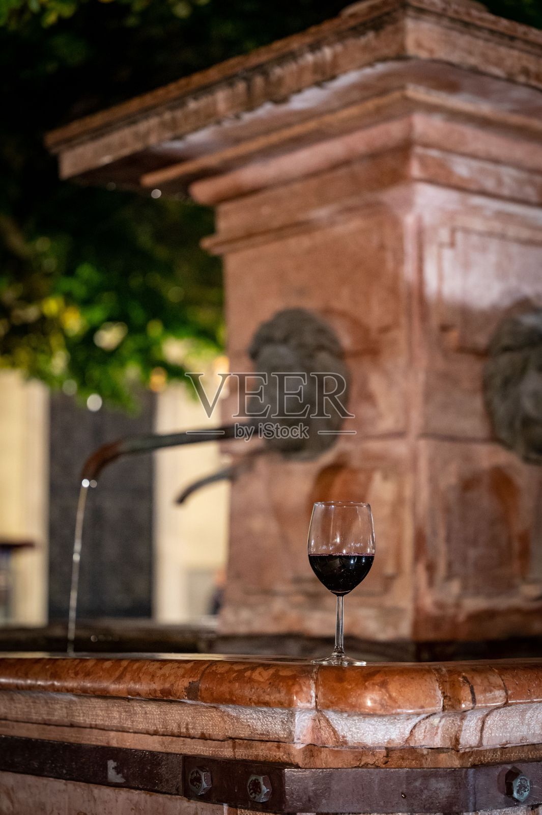 垂直浅焦点镜头的一杯红酒在石头喷泉照片摄影图片