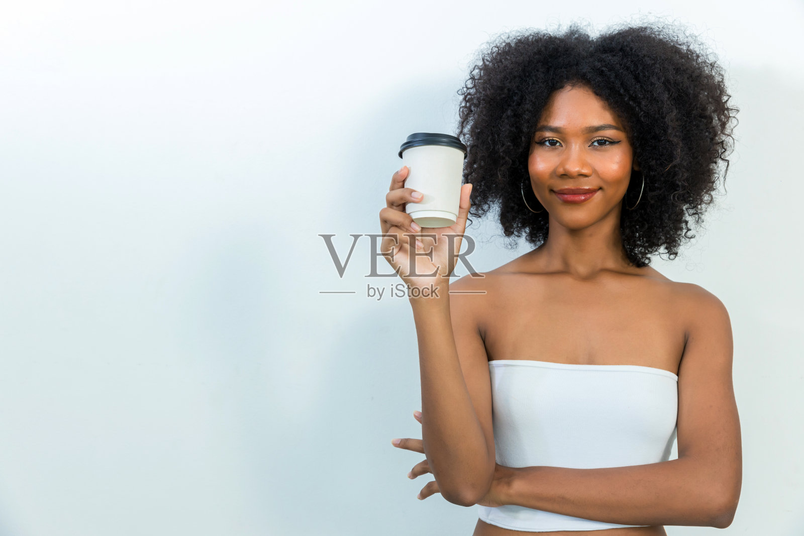 快乐的年轻女子在家里享受一杯咖啡。拿着咖啡纸杯的女人照片摄影图片