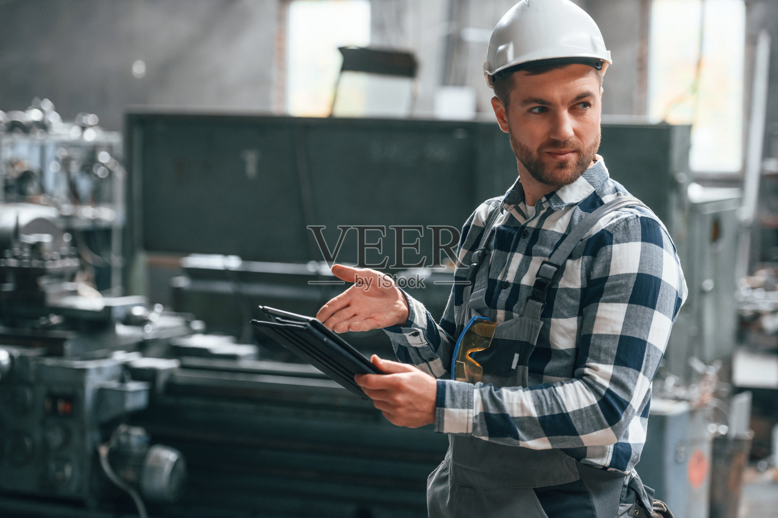 站立和使用图形平板。穿制服的工厂男工人在室内照片摄影图片