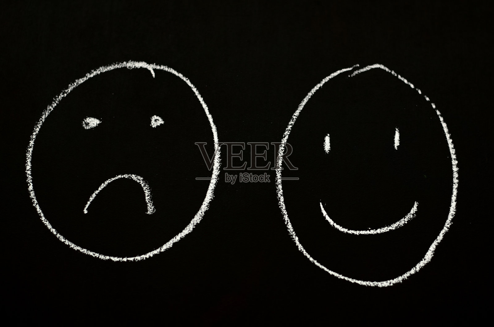 黑板上画着微笑和悲伤的脸照片摄影图片