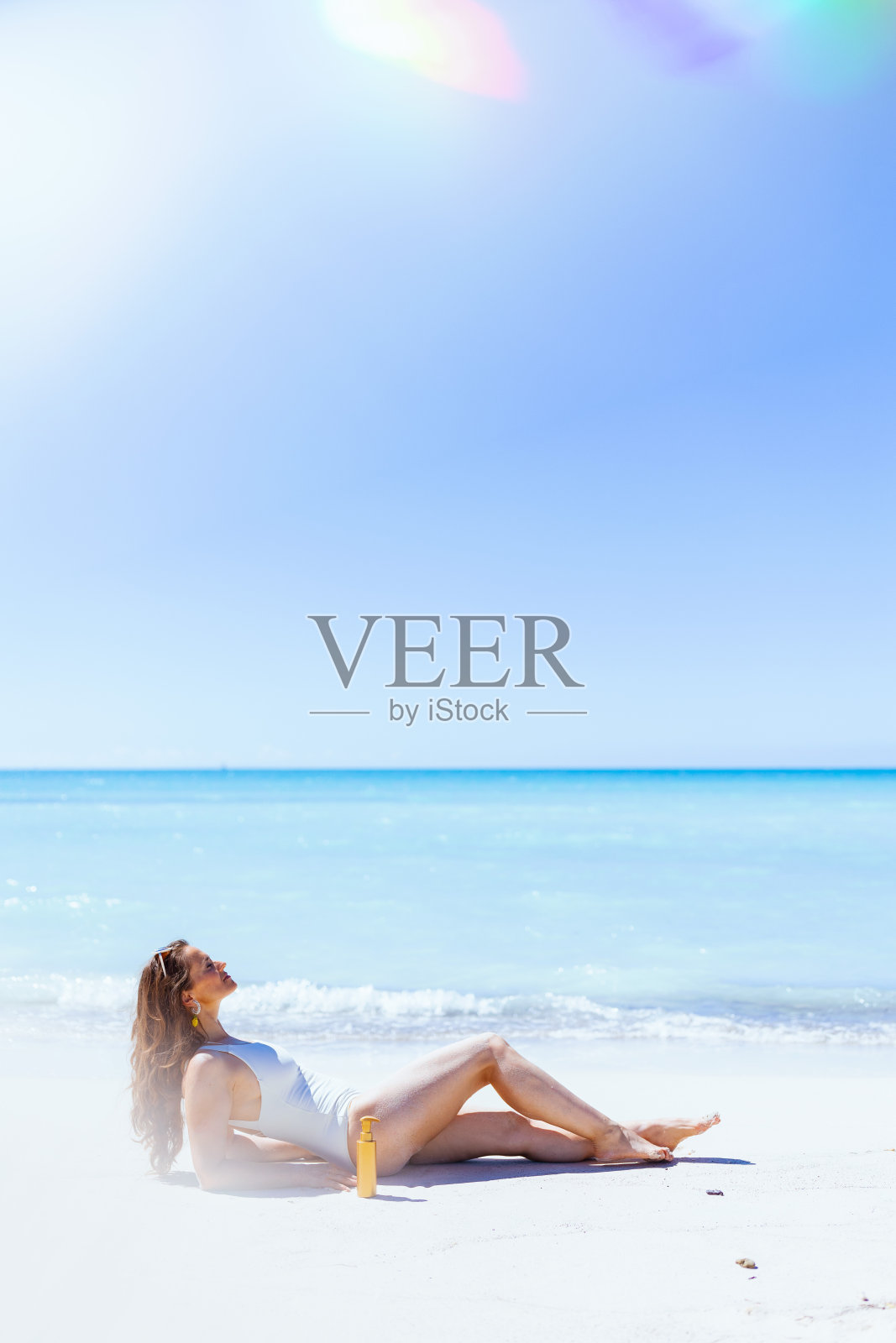 放松优雅的女人在白色泳衣躺在海滩上照片摄影图片