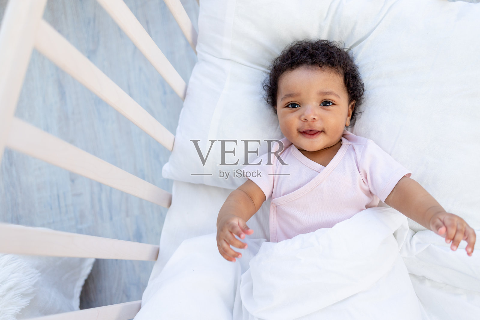 非裔美国男婴在睡觉前躺在床上，或者早上醒来微笑照片摄影图片