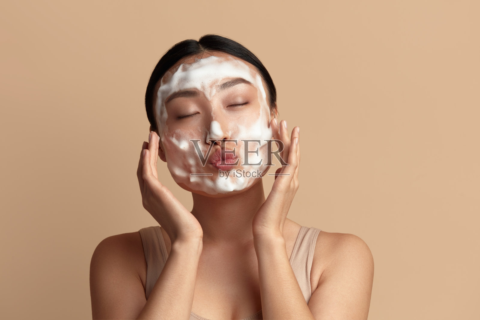 面部皮肤护理。有趣的亚洲女人用泡沫肥皂清洁面部皮肤照片摄影图片