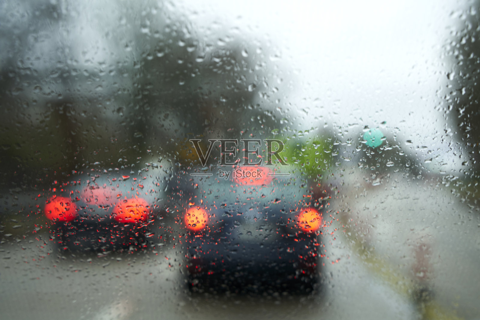 雨点打在挡风玻璃上。在雨中开车。装有刹车灯的车辆。照片摄影图片