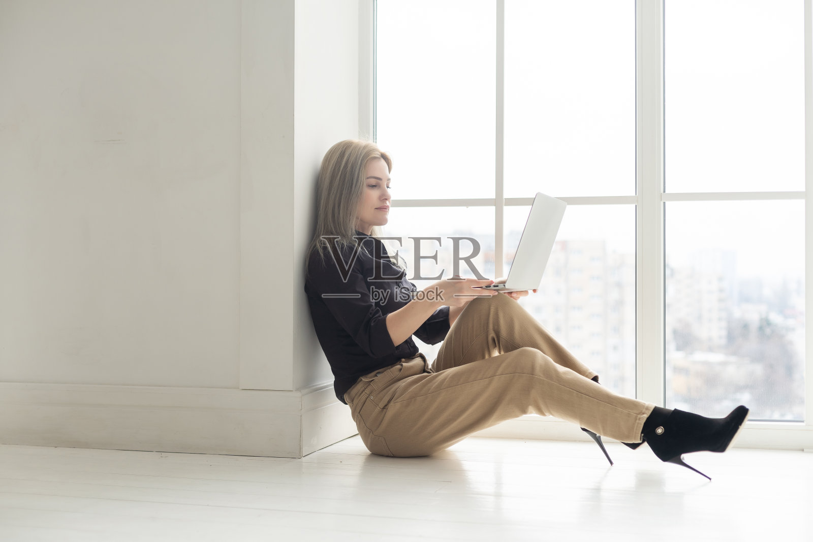 年轻美丽快乐的女人微笑着在办公室用笔记本电脑工作的形象。照片摄影图片