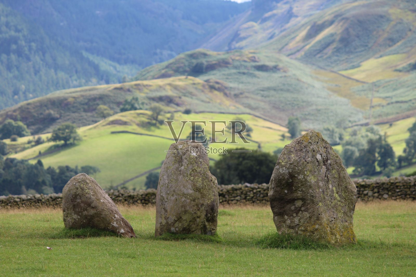 草地上的岩石，背景是风景秀丽的山脉和景观照片摄影图片