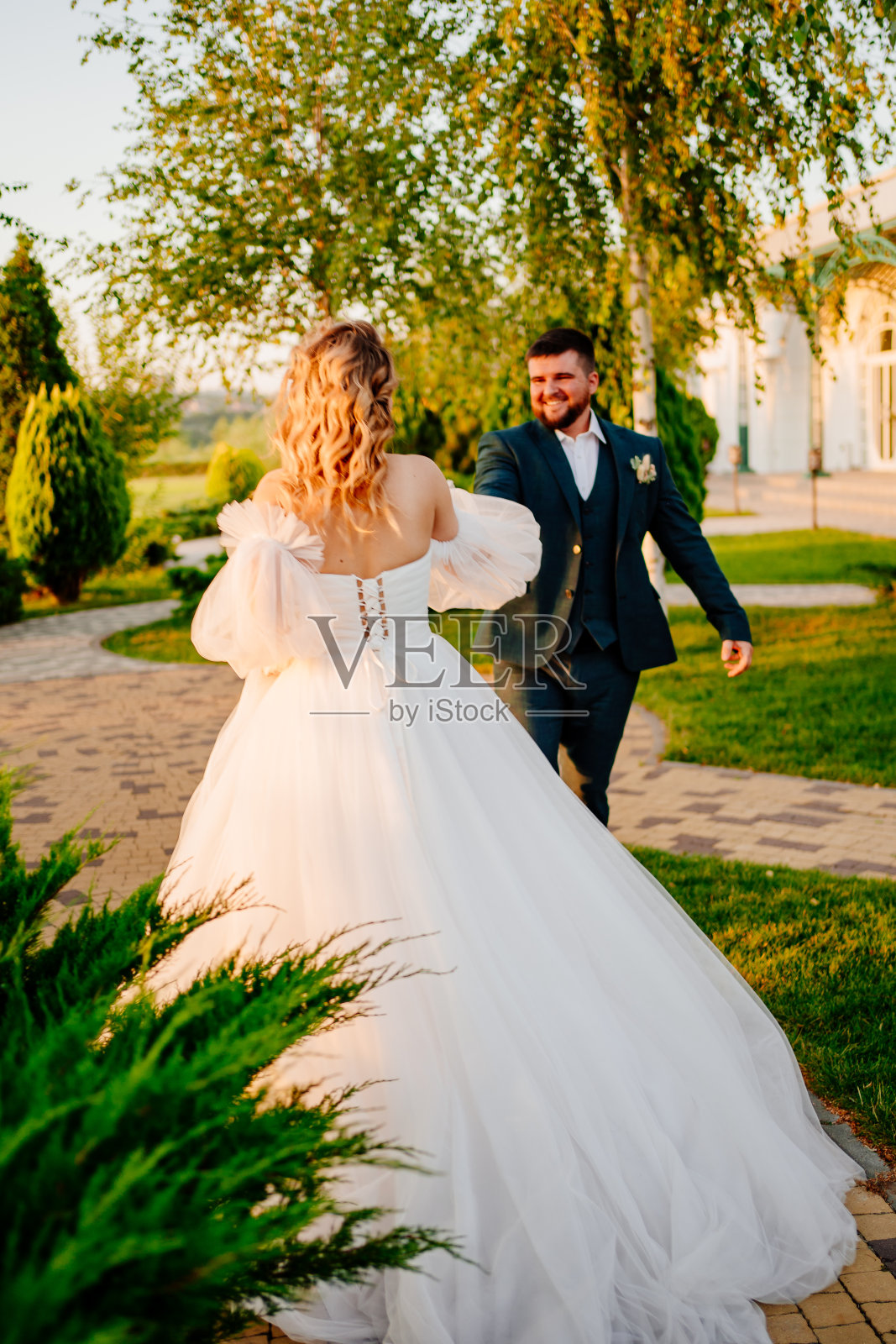 新娘和新郎手牵着手沿着小路走照片摄影图片