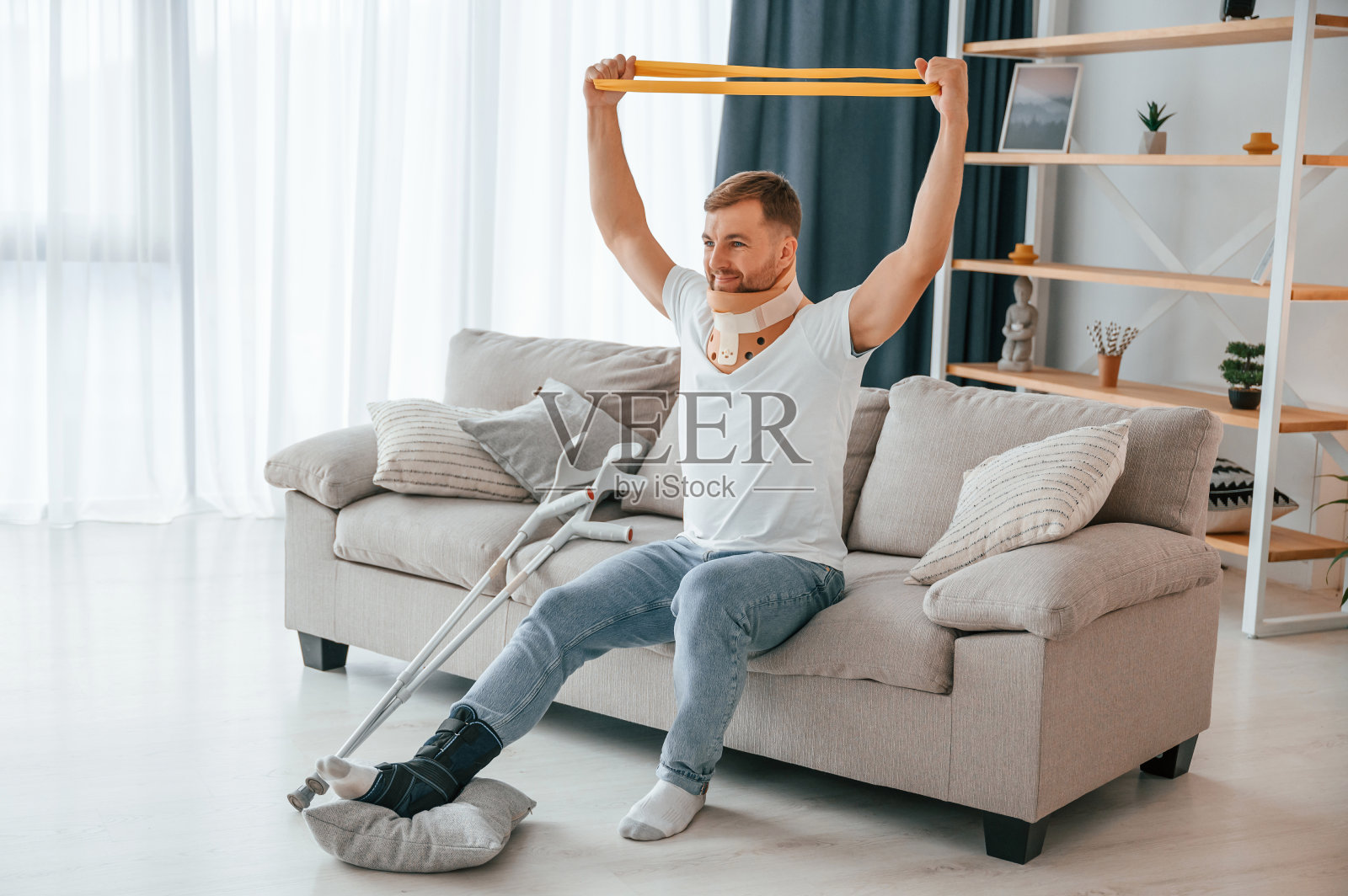 手臂康复训练。拄着拐杖的男人在家。有伤害照片摄影图片