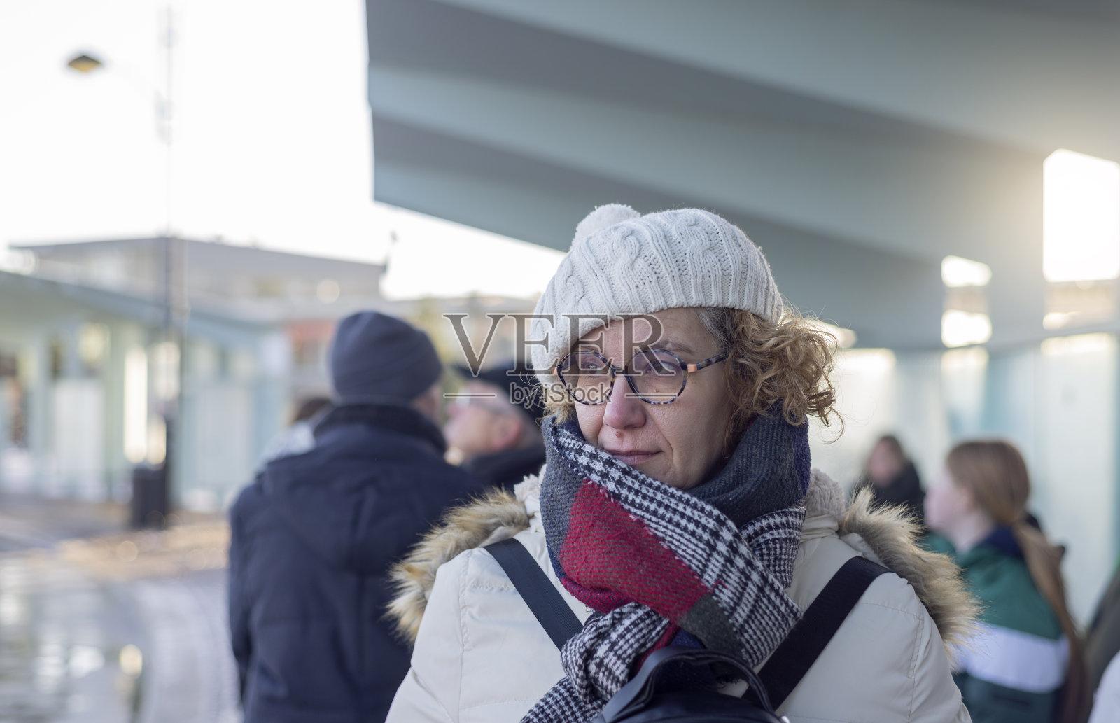 一个成年女子的肖像与围巾和白色帽子在公共汽车站照片摄影图片